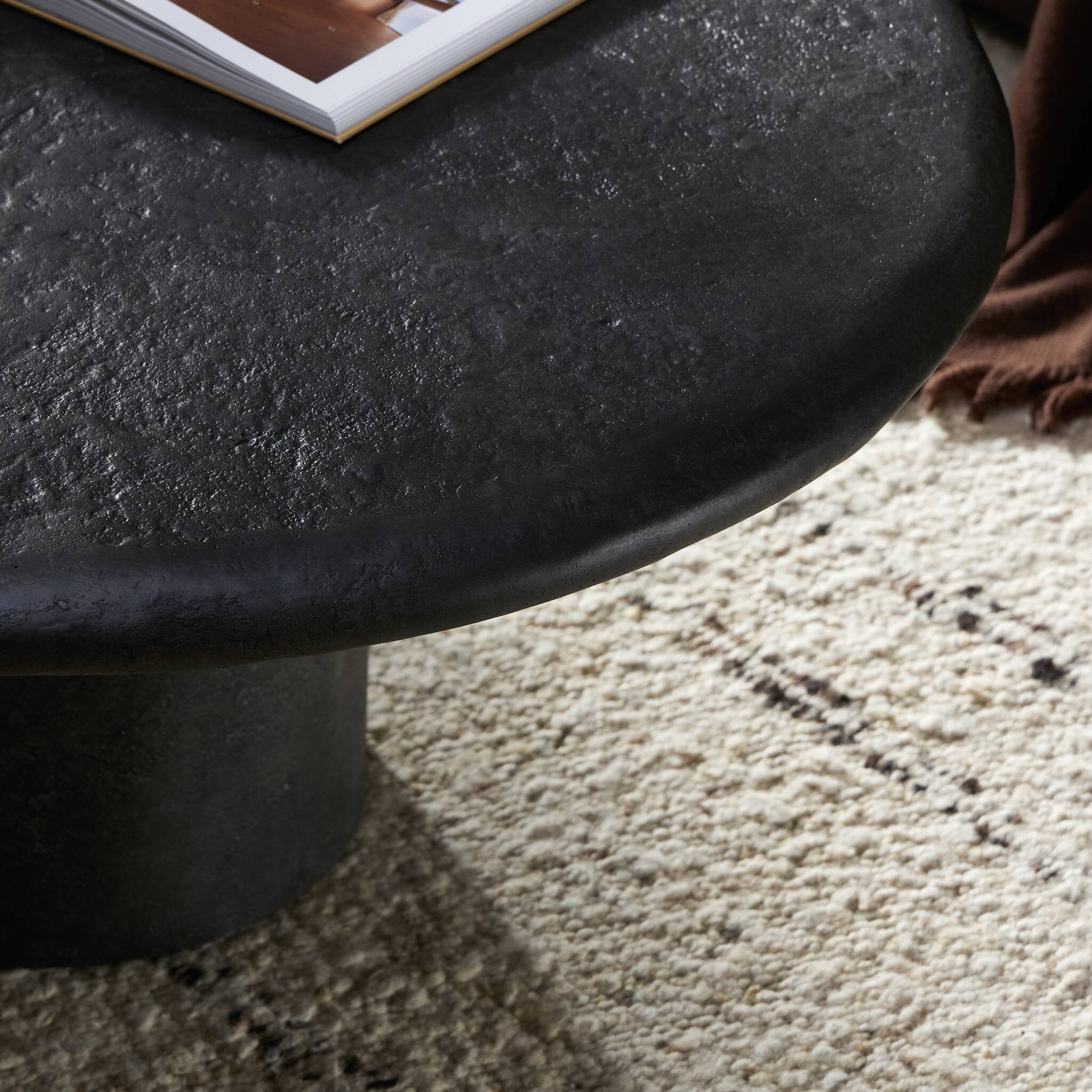 Round black stone table on a textured beige carpet