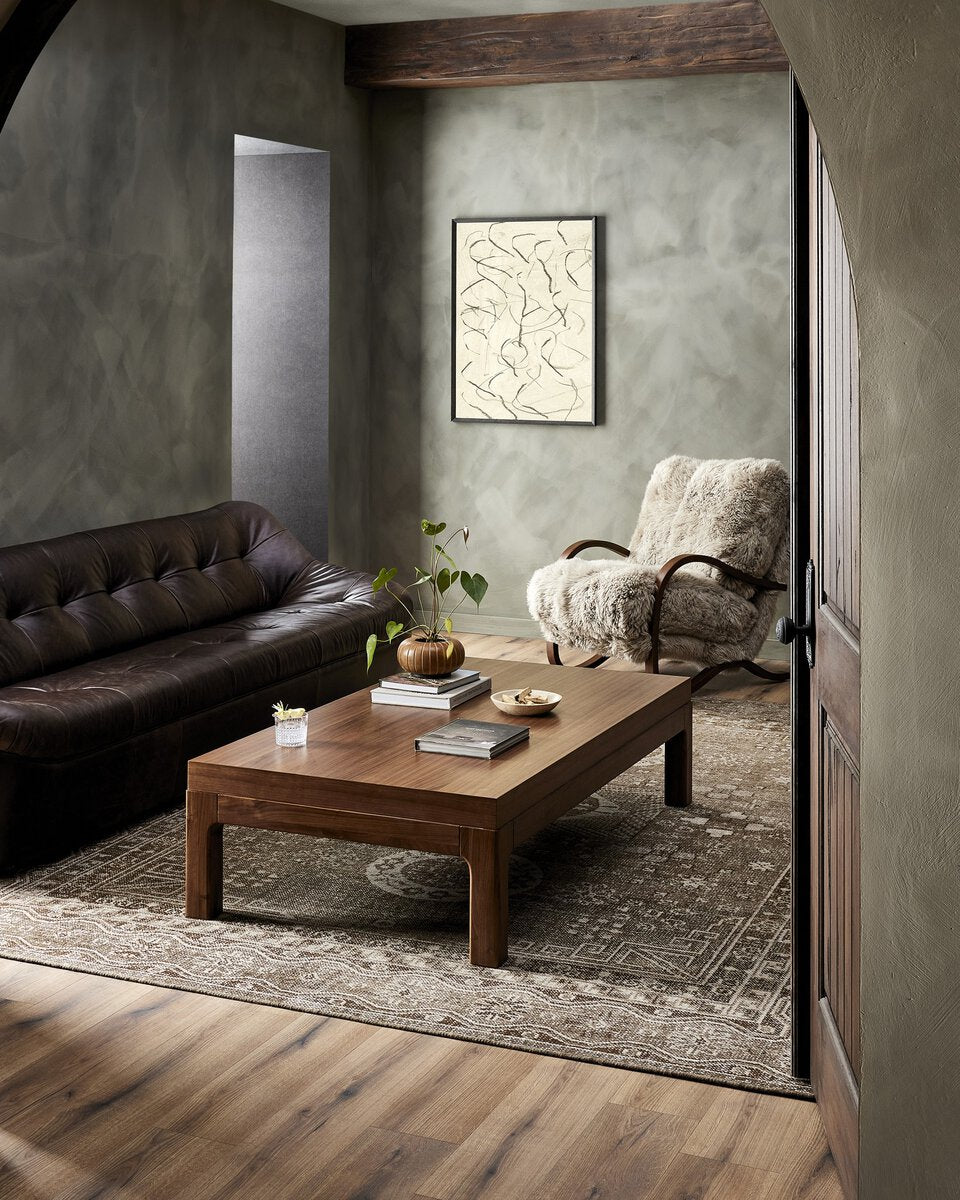 Living room with a brown leather sofa, wooden coffee table, and armchair.
