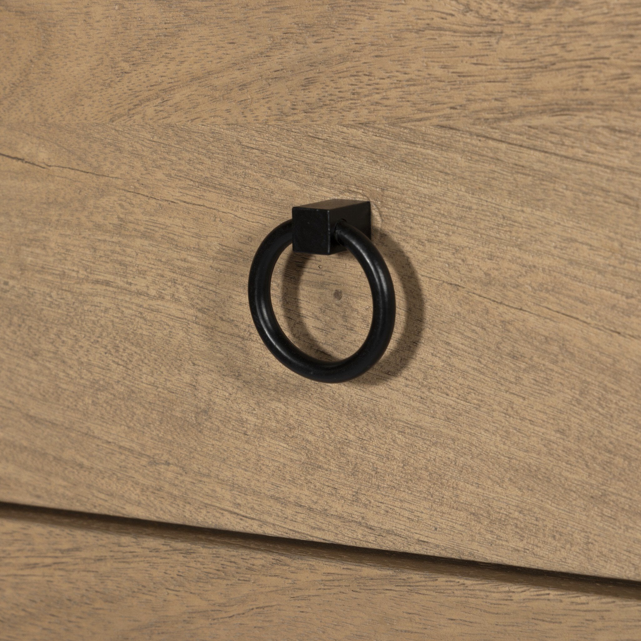 Close-up of a black ring handle on a wooden surface