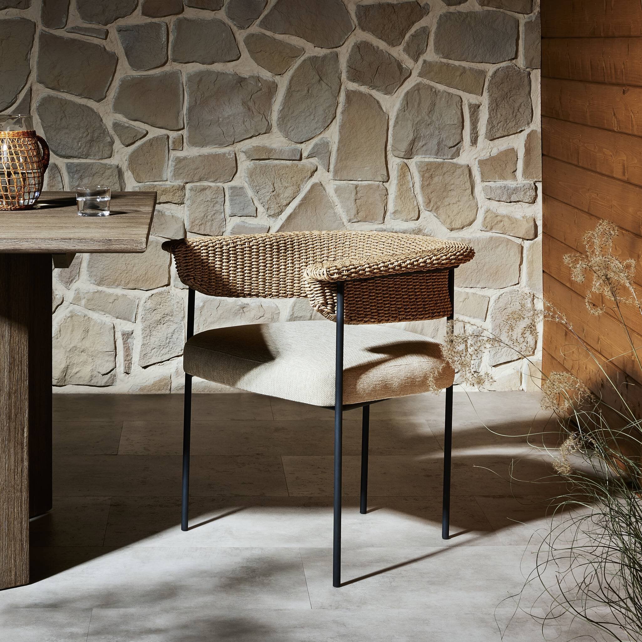 Wicker chair against a stone wall with wooden table
