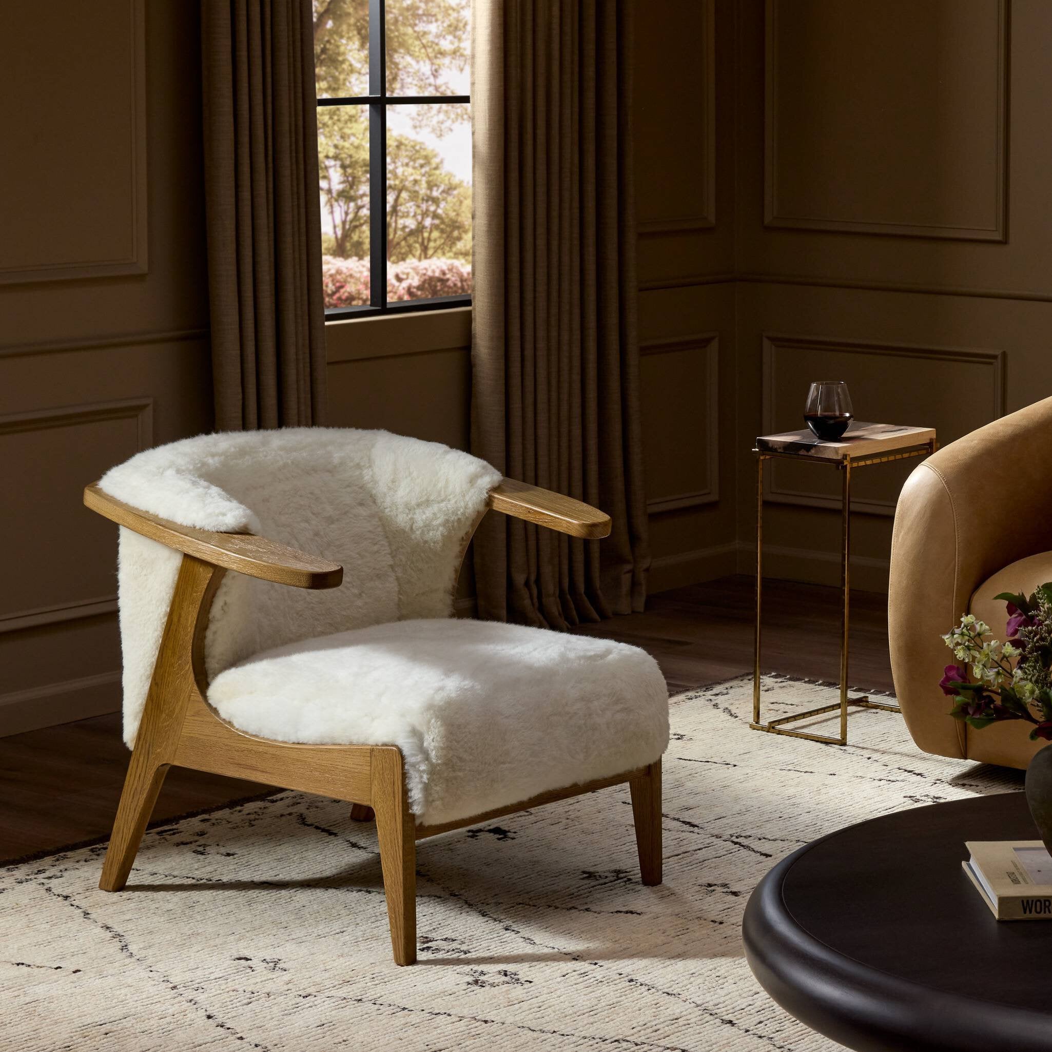 Wooden armchair with white fur in a stylish room with a window and side table.