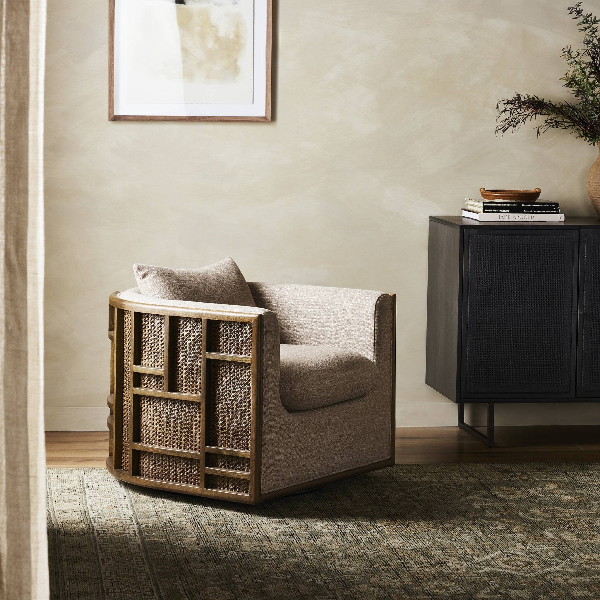 Modern armchair with wicker side table in a room with a cabinet and plant.