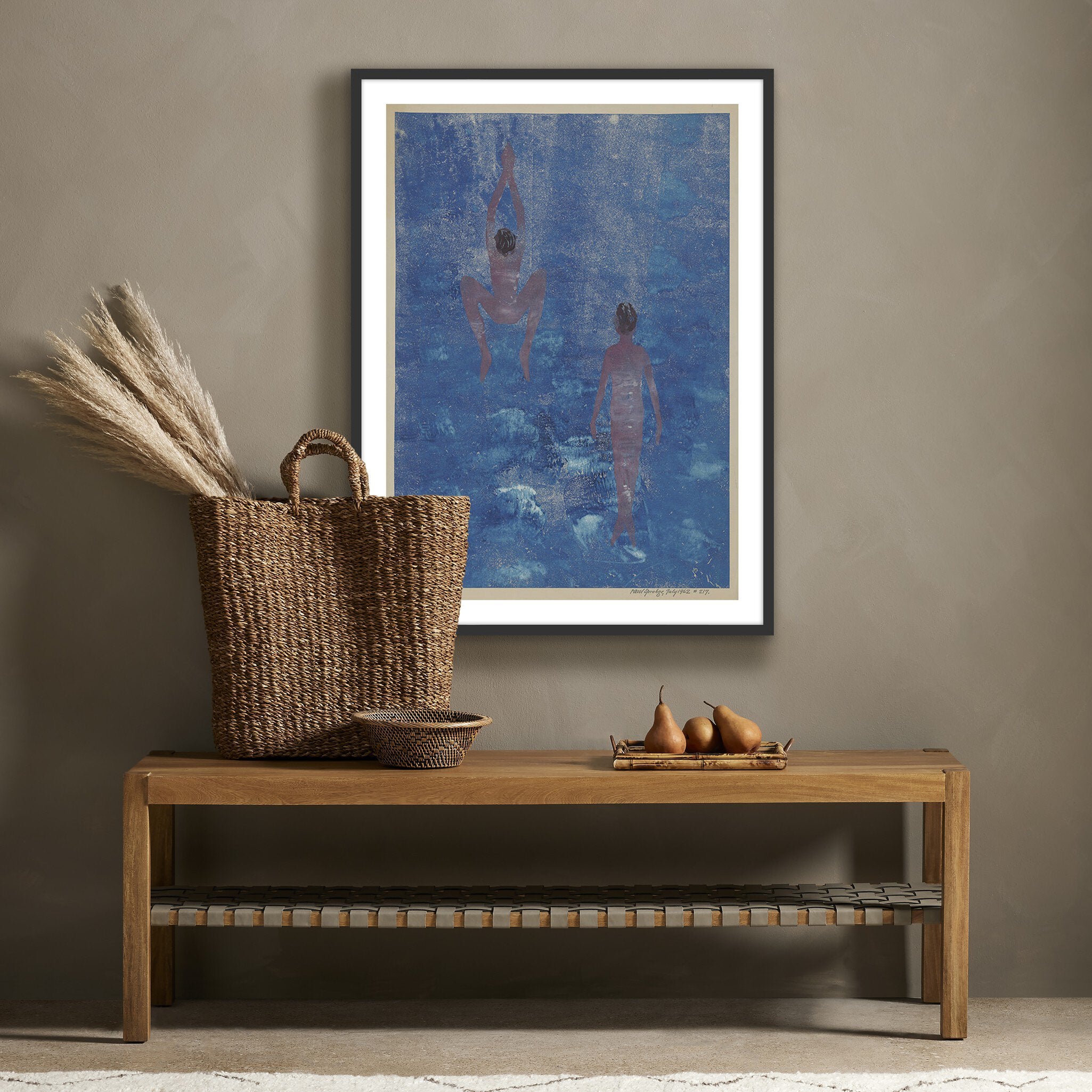 Framed abstract artwork on a wall above a wooden bench with decorative items.
