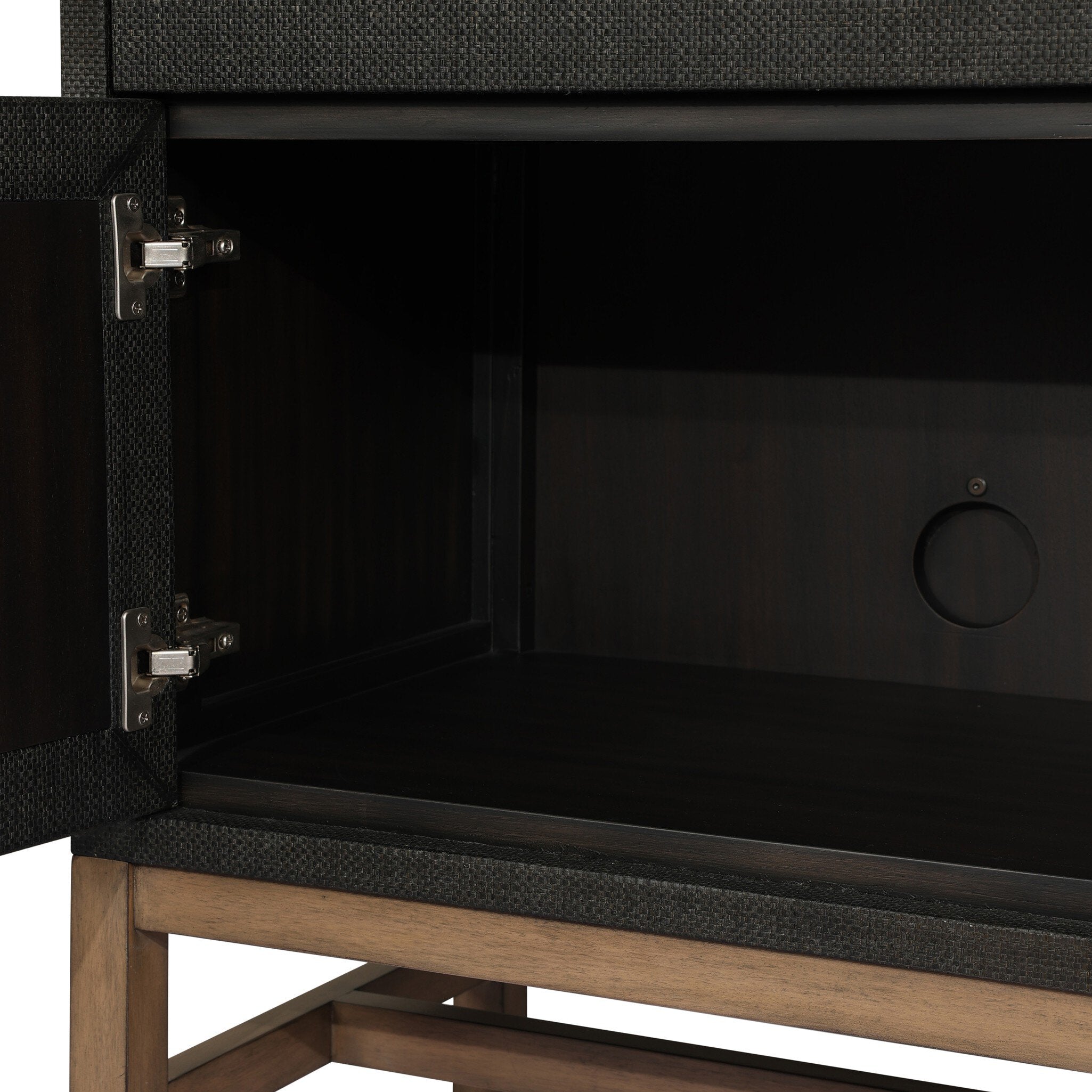 Close-up of a black cabinet with cord management port and wooden legs on a white background