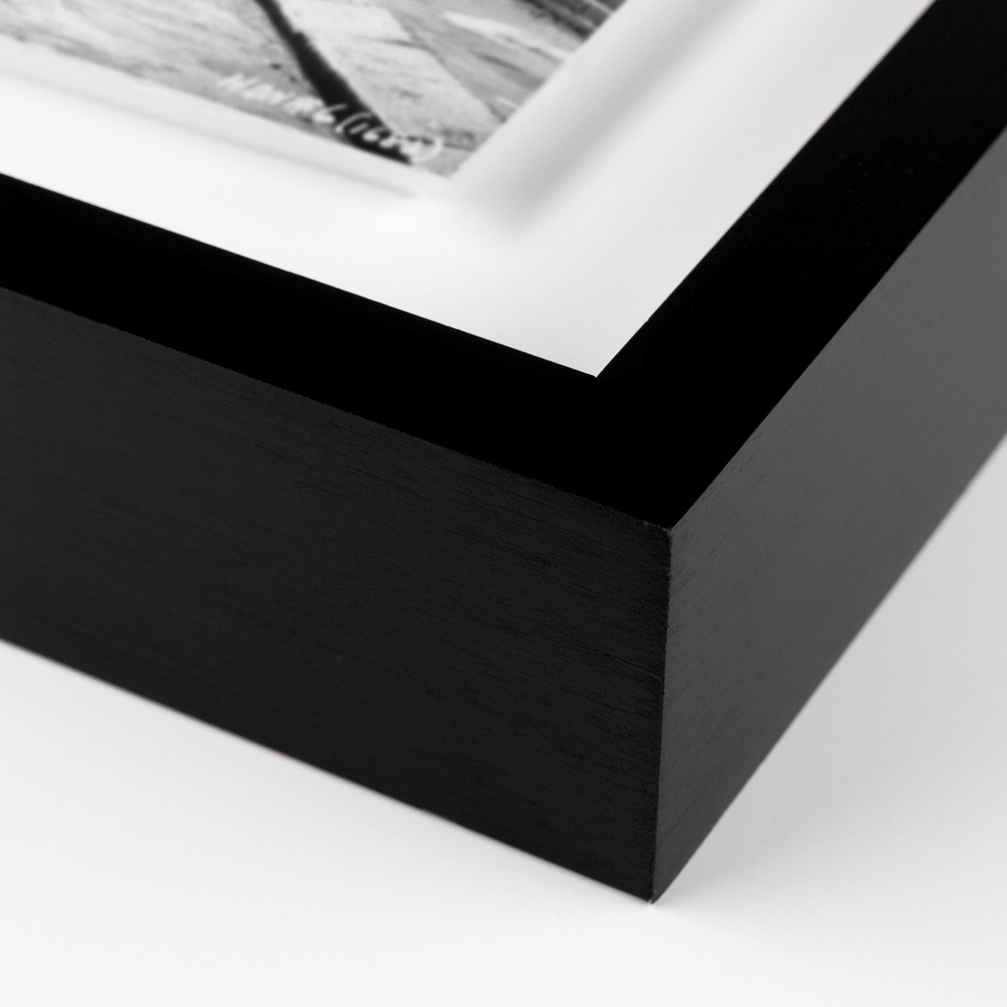 Close-up of a black picture frame corner with a white mat and photo inside.