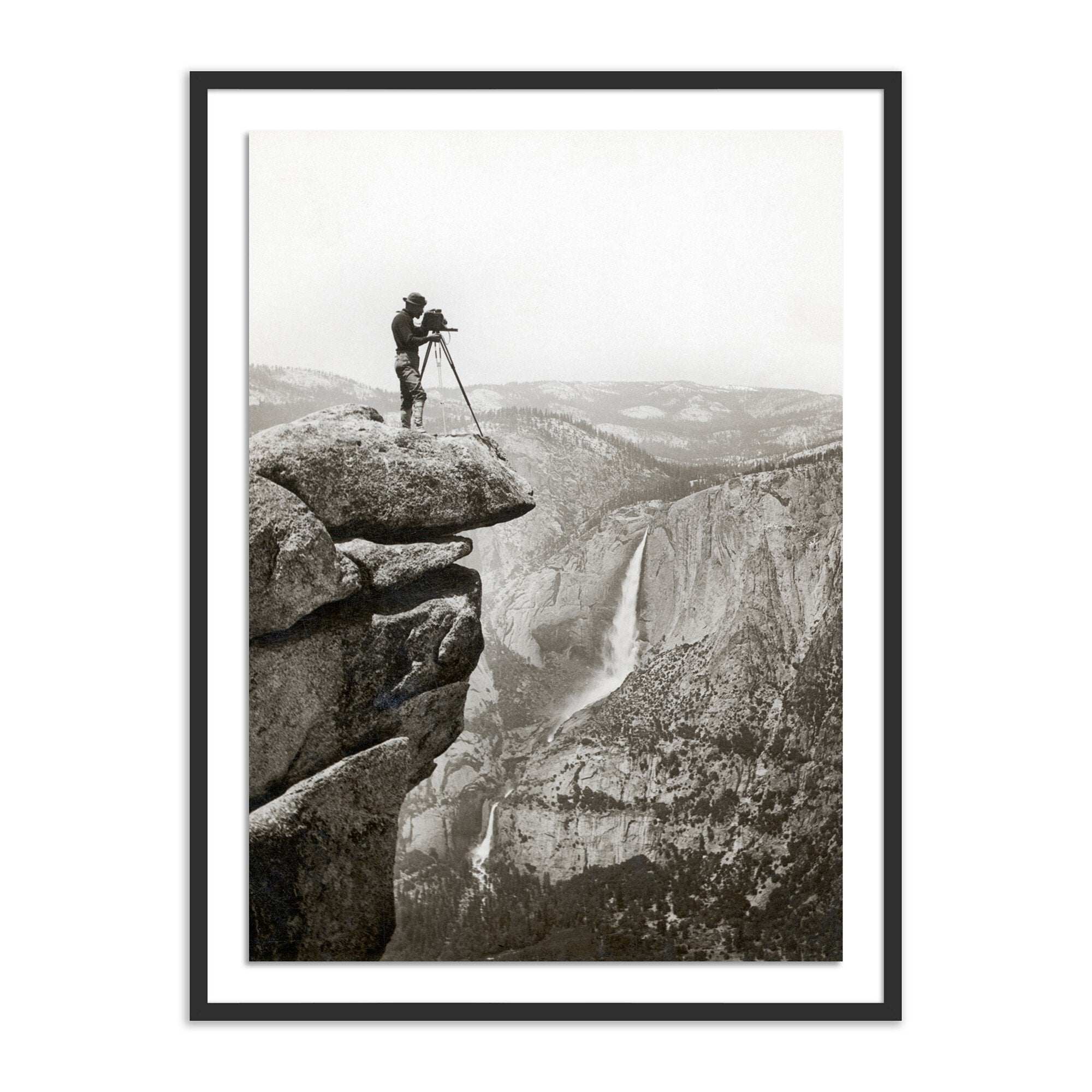 Framed black and white photograph of a person on a rocky outcrop with a landscape in the background.
