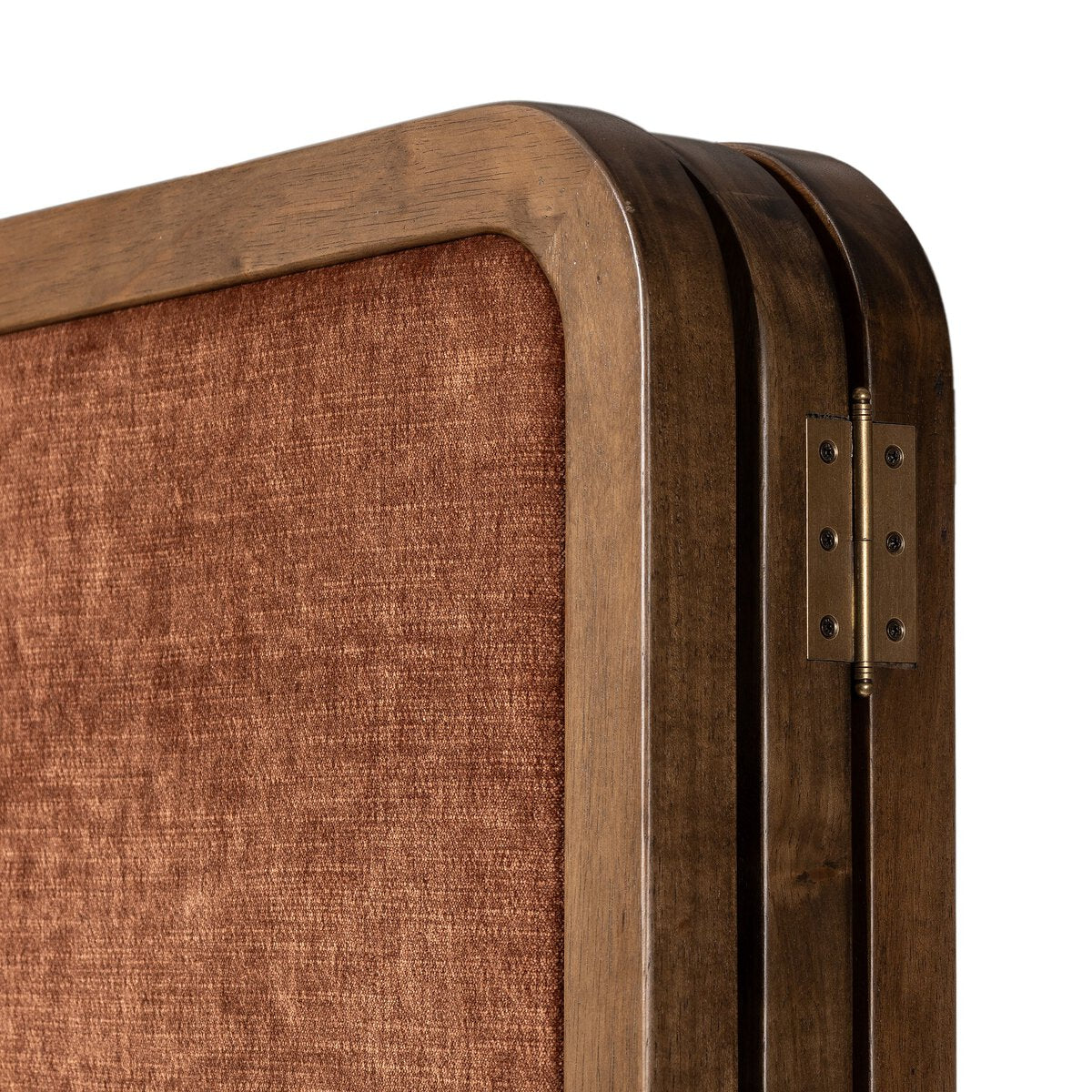 Close-up of a wooden room divider with a rust brown fabric surface and brass hinge.