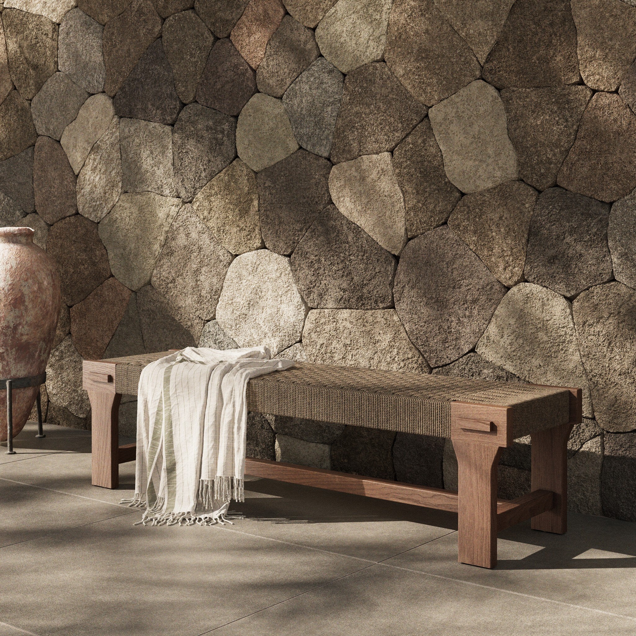 Wooden bench with a blanket against a stone wall
