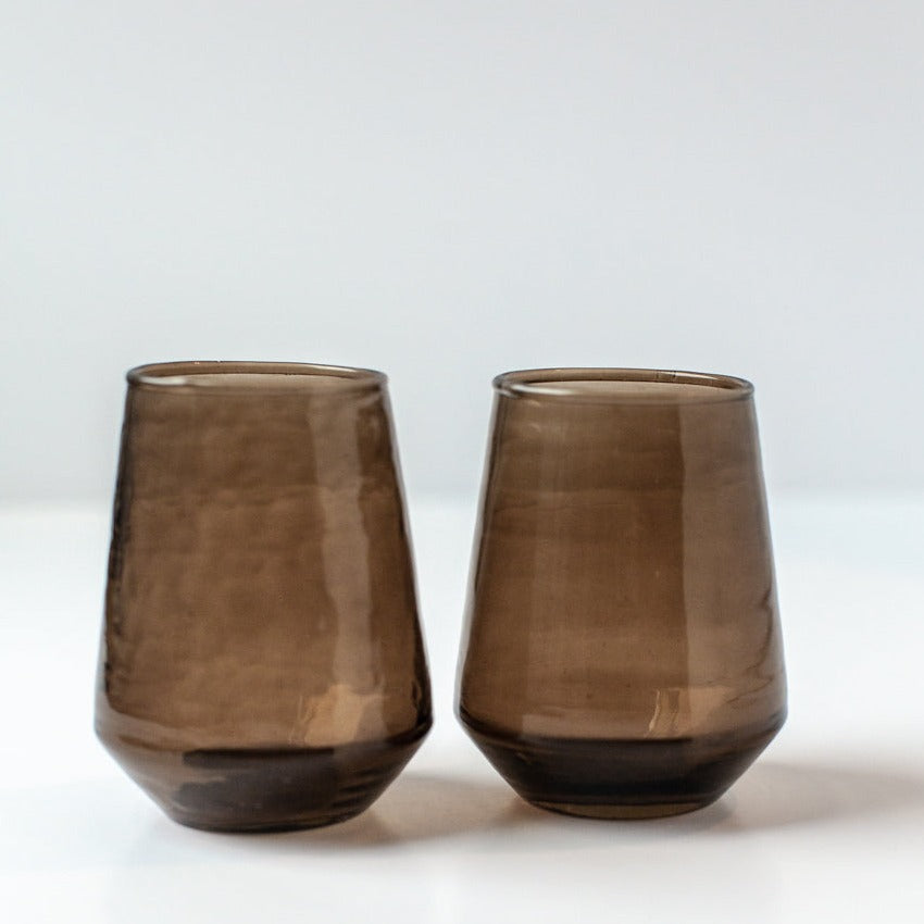 Two brown glass tumblers on a white background