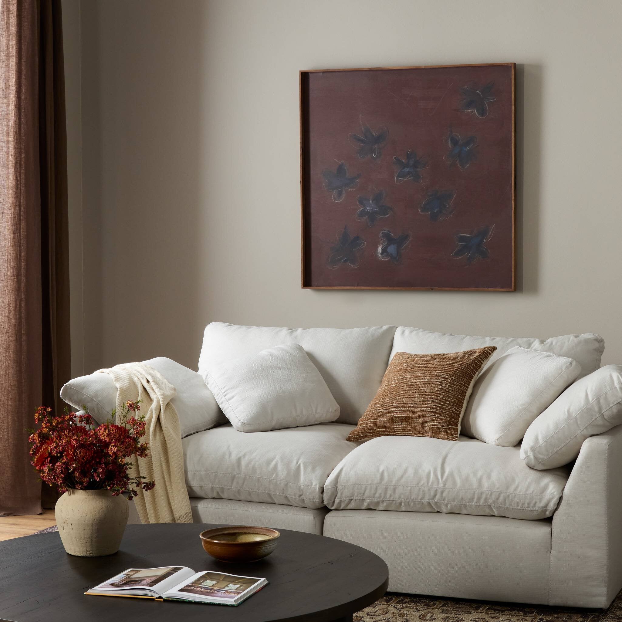 Living room with a white sofa, coffee table, and abstract painting on the wall.