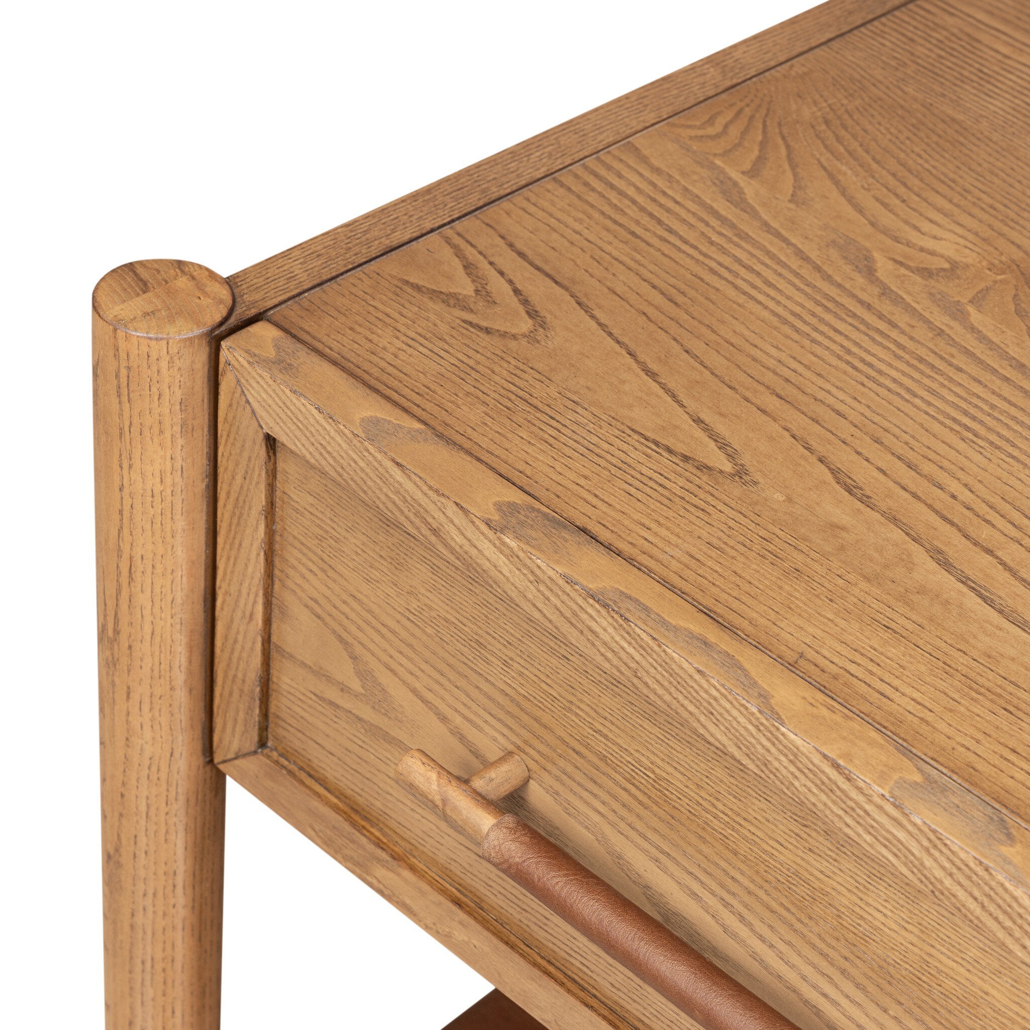 Close-up of a wooden furniture piece showing the grain of medium brown wood, a drawer front, and part of a matching leg against a white background.