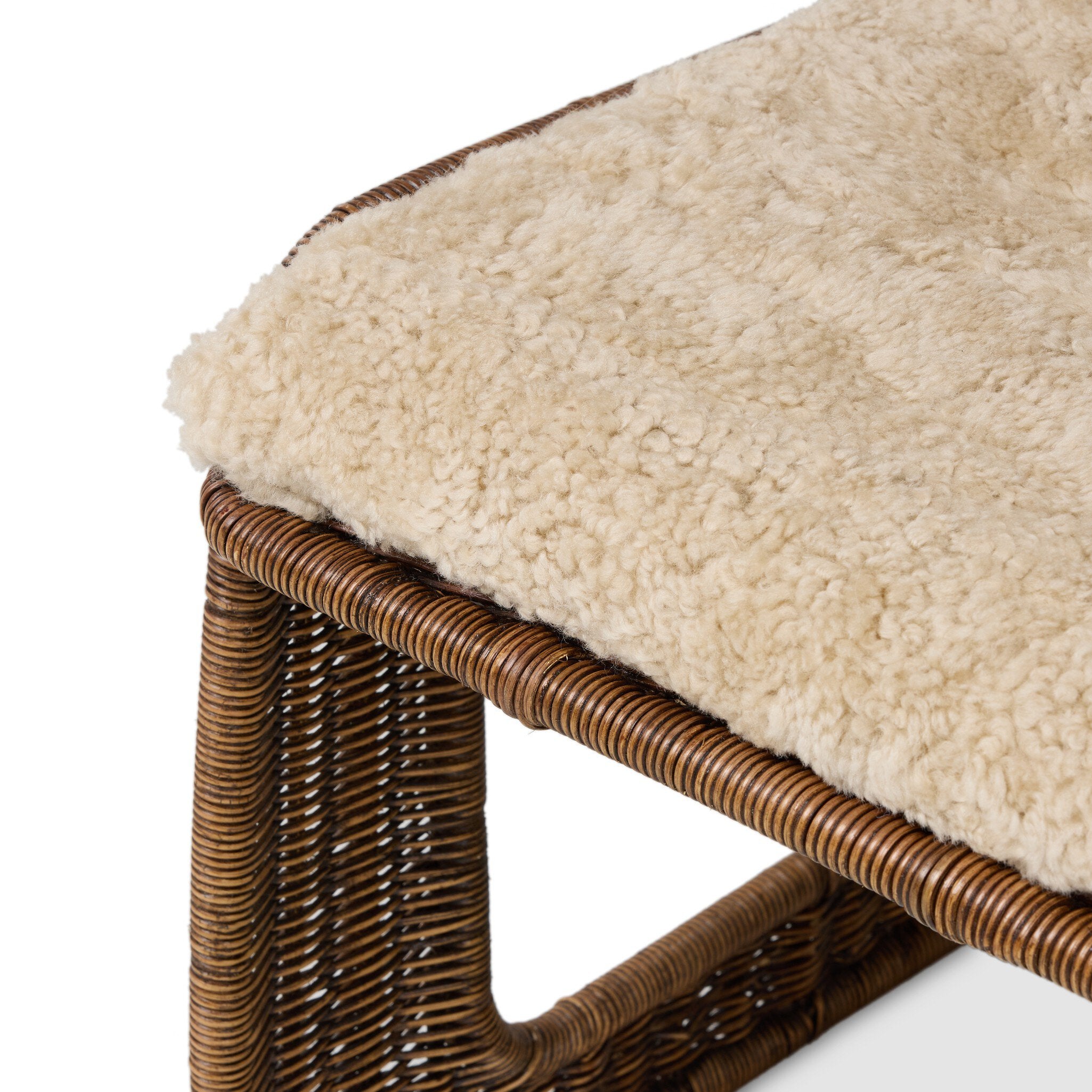 Wicker ottoman with a plush beige cushion on a white background
