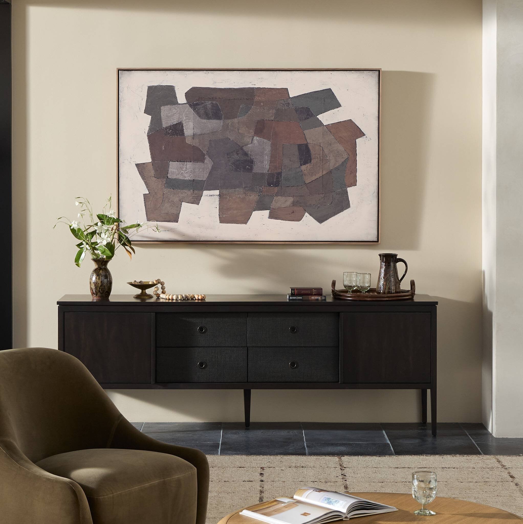 Living room with a dark wooden sideboard, abstract painting, and armchair.