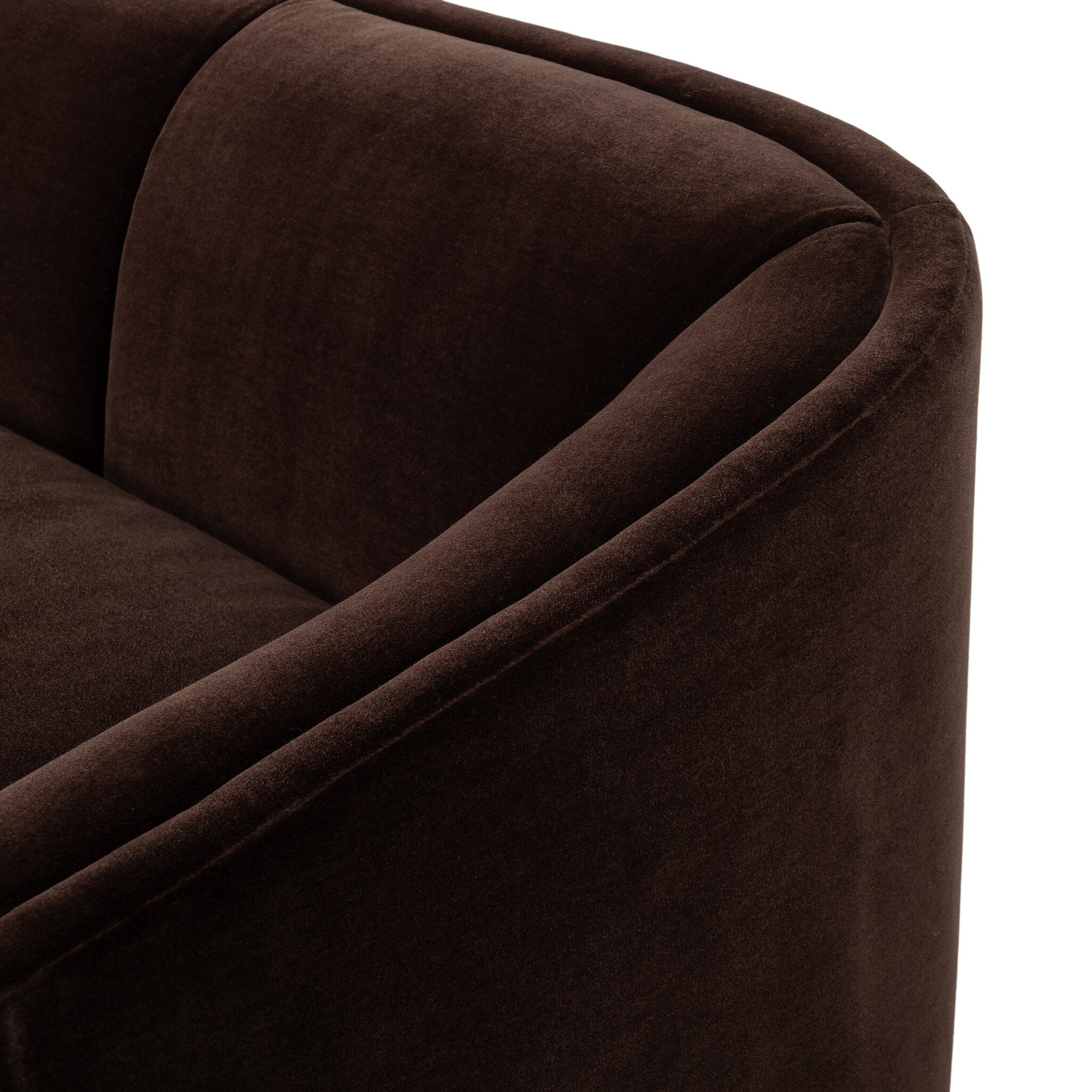 Close-up of a dark brown velvet upholstered armchair showing the curved armrest and back cushion against a plain white background.