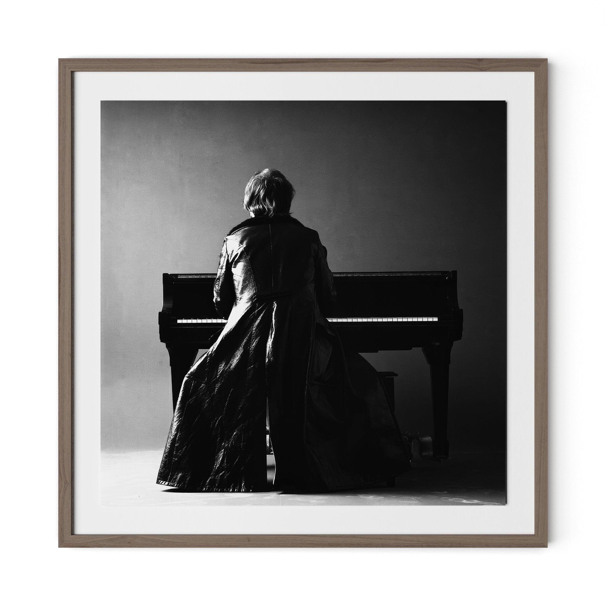 Framed black and white photograph of a Elton John sitting at a piano.
