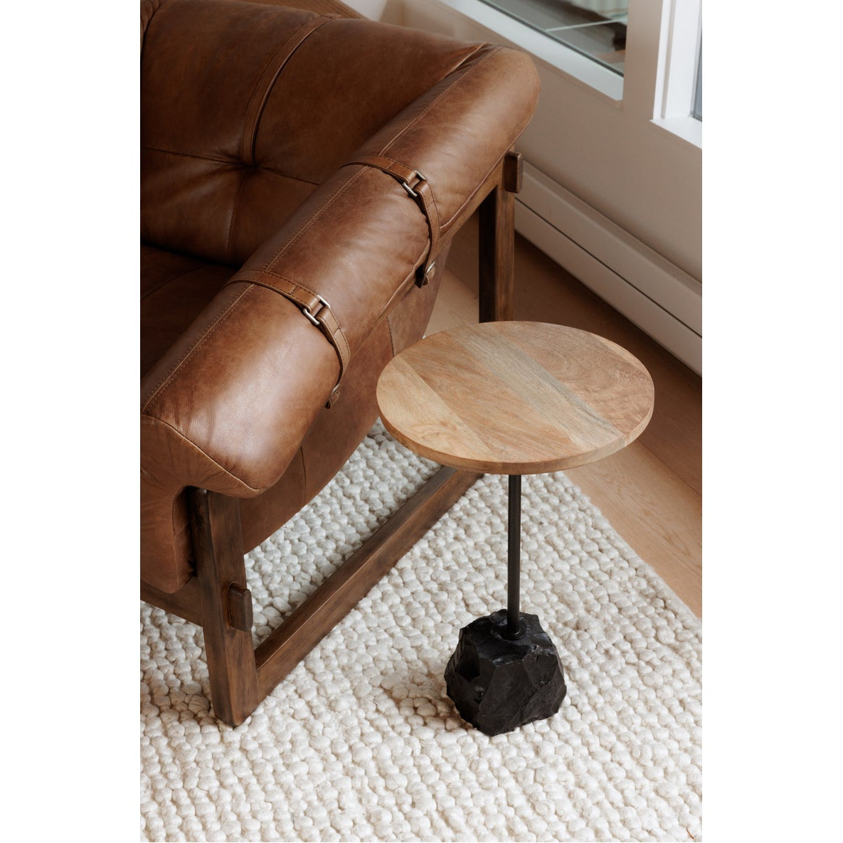 Brown leather armchair with a small round wooden table in a room.
