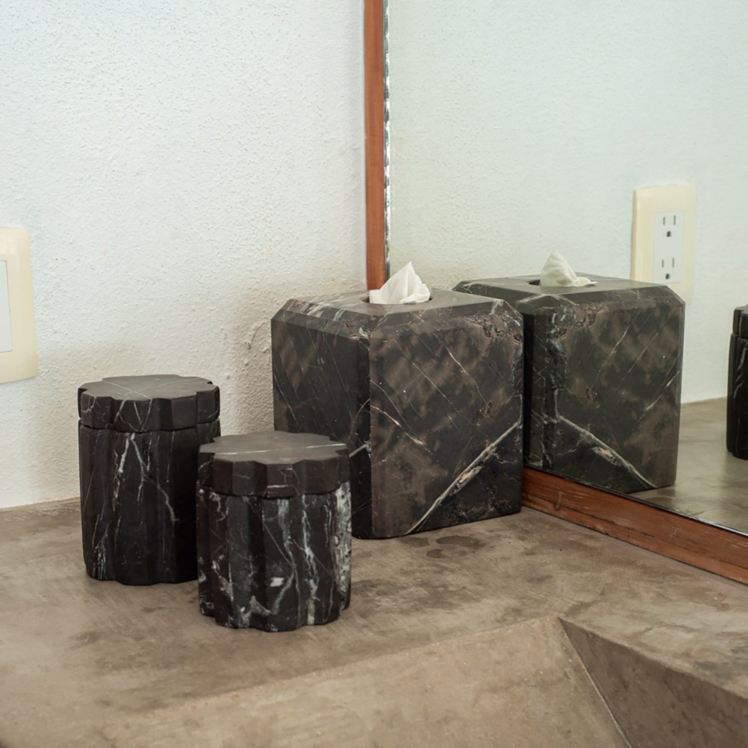 Set of marble-textured storage boxes on a concrete tabletop with a mirror in the background.