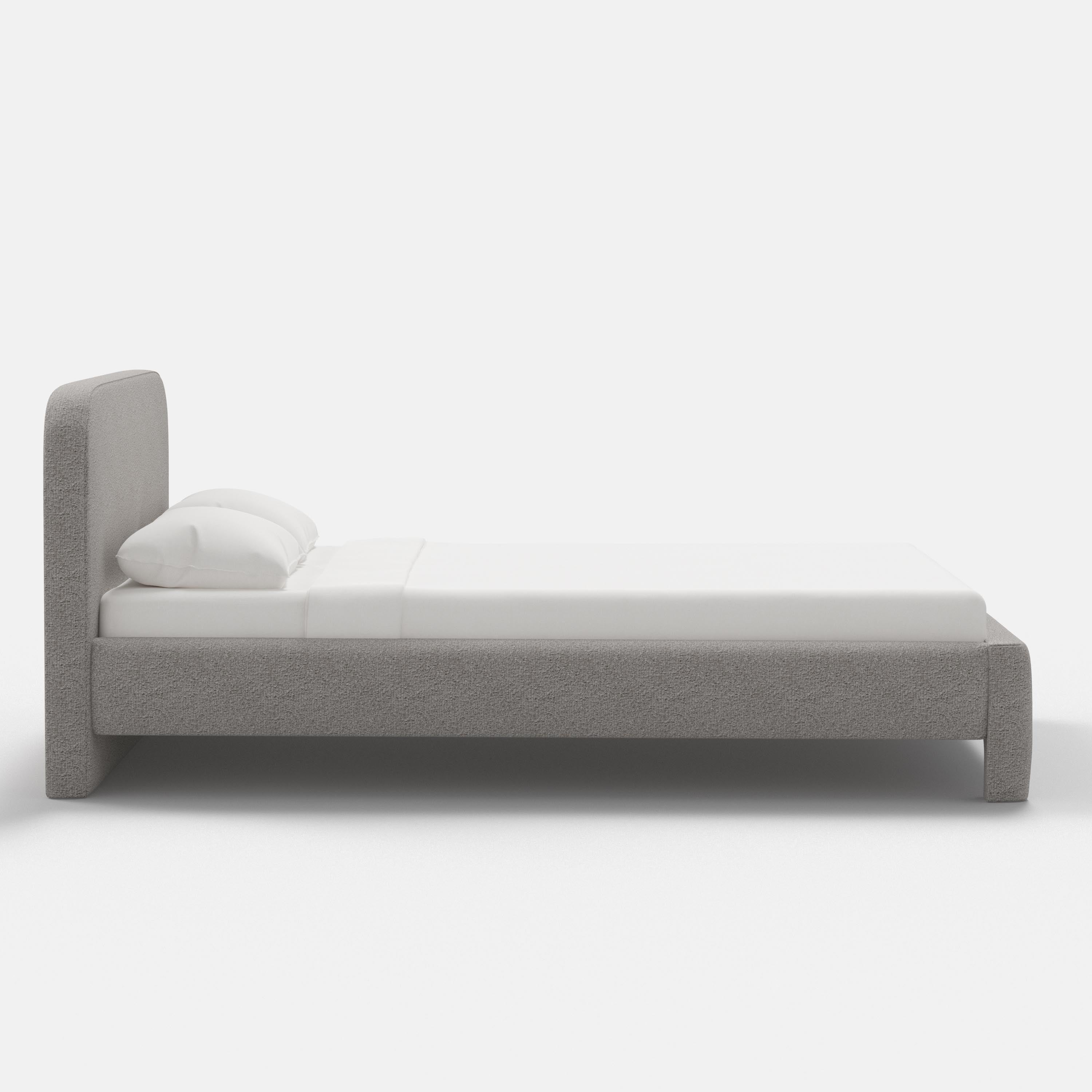Gray upholstered bed with white bedding on a white background