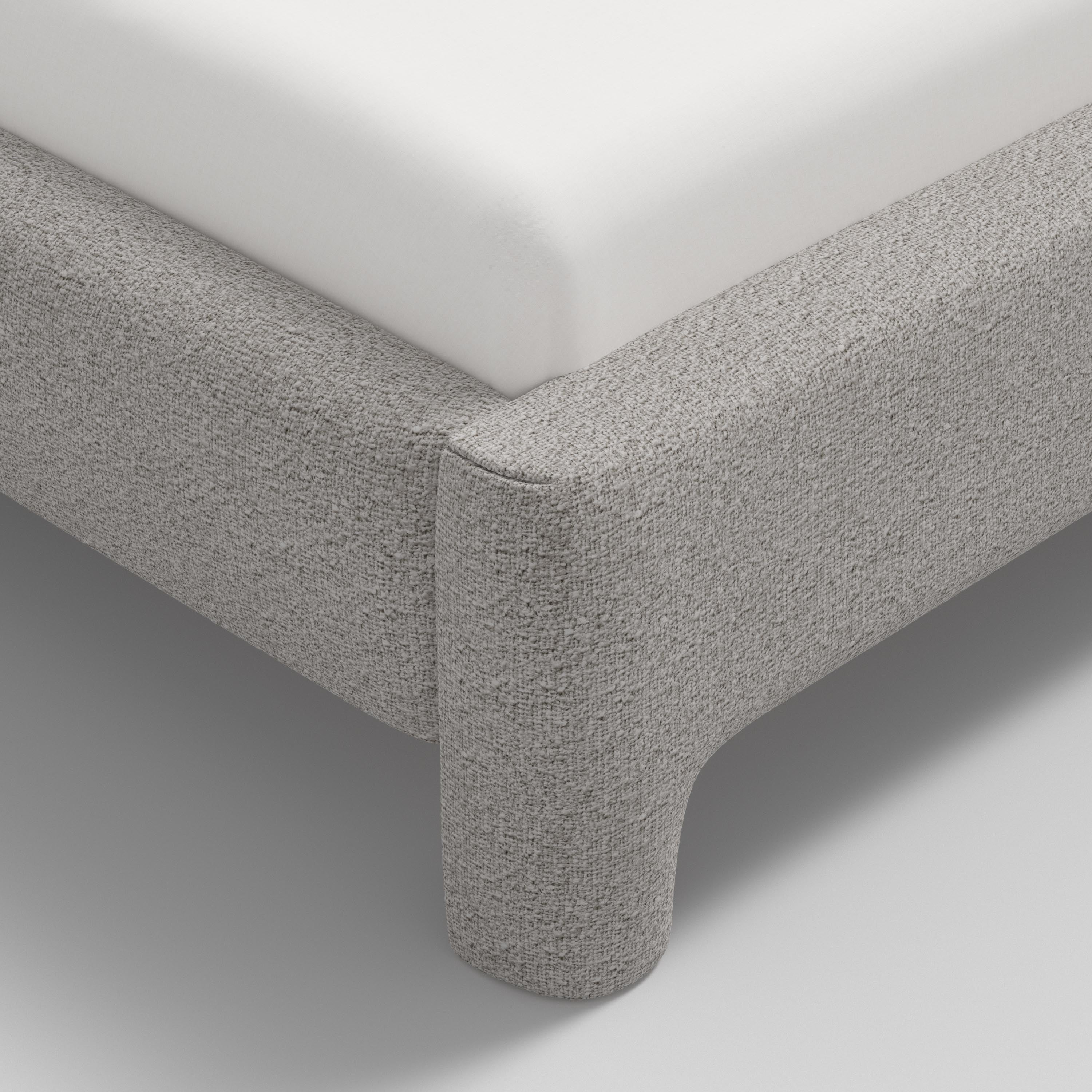 Gray upholstered bed with white bedding on a white background