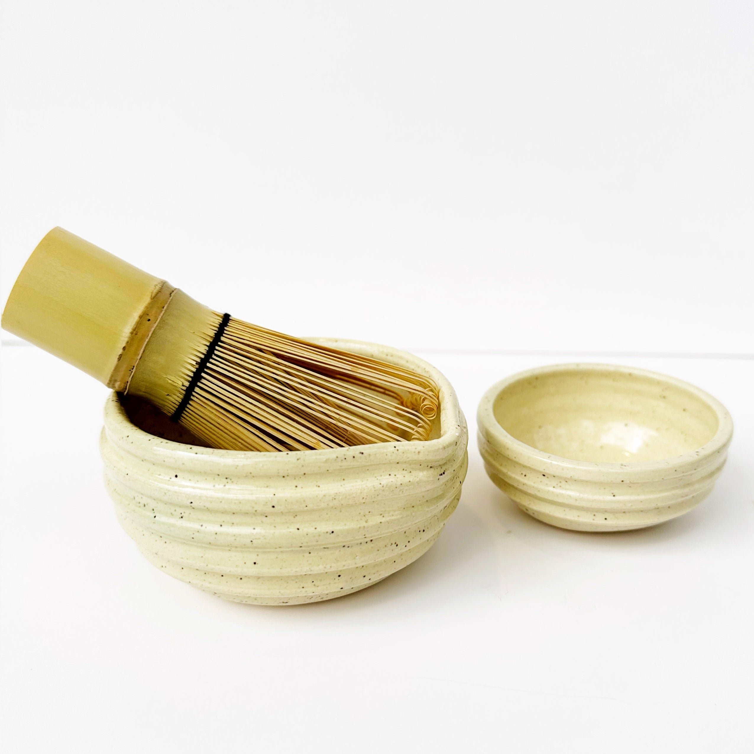 Traditional Japanese tea-making set with a whisk and two bowls on a white background