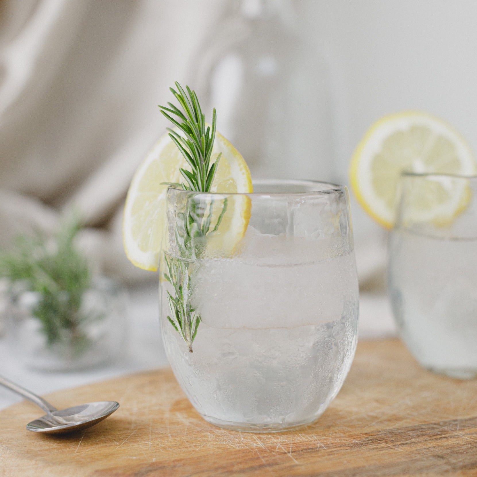 Clear glass with lemon and rosemary garnish on a wooden surface
