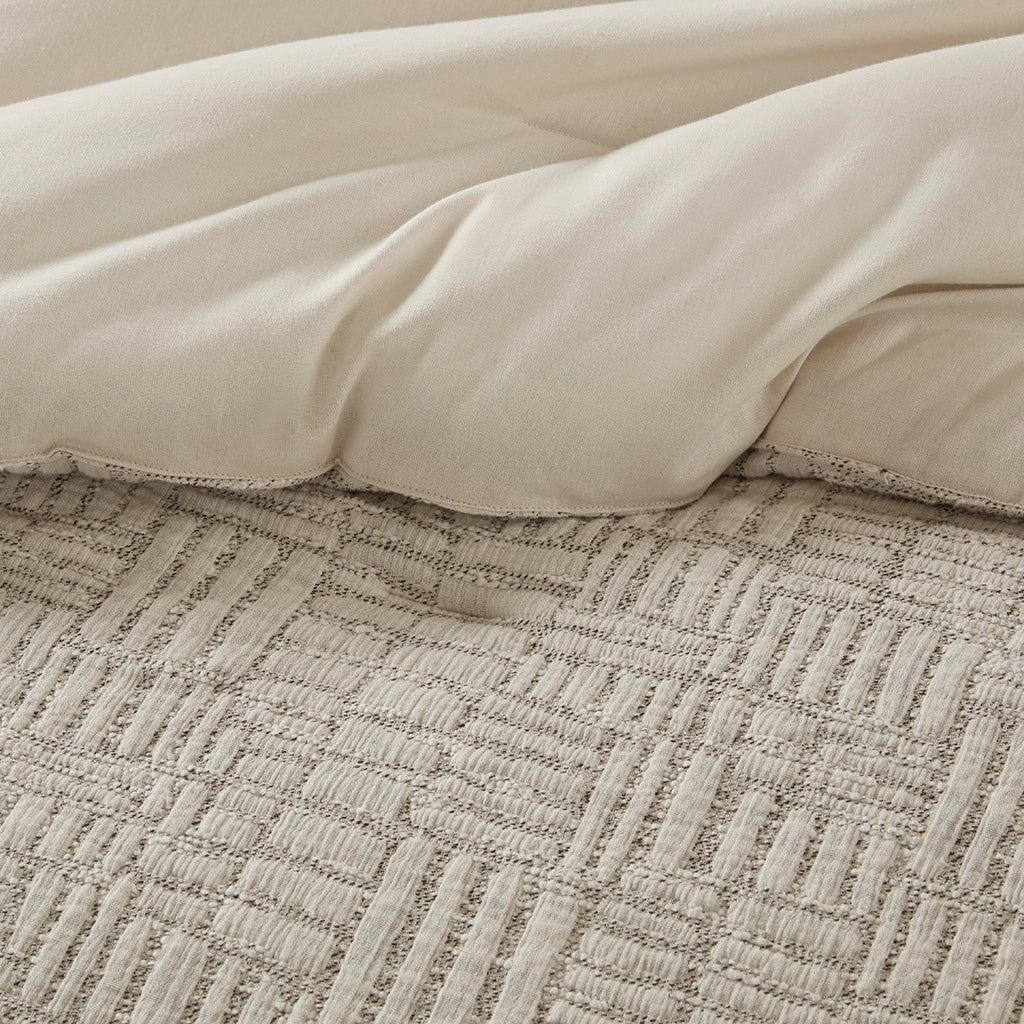 Close-up of beige comforter on a textured bedspread