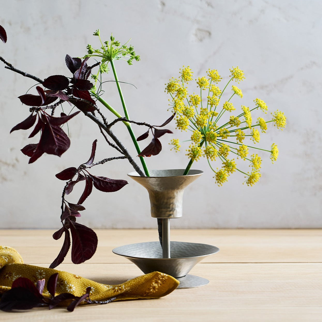 Decorative vase with plants on a wooden surface against a neutral background