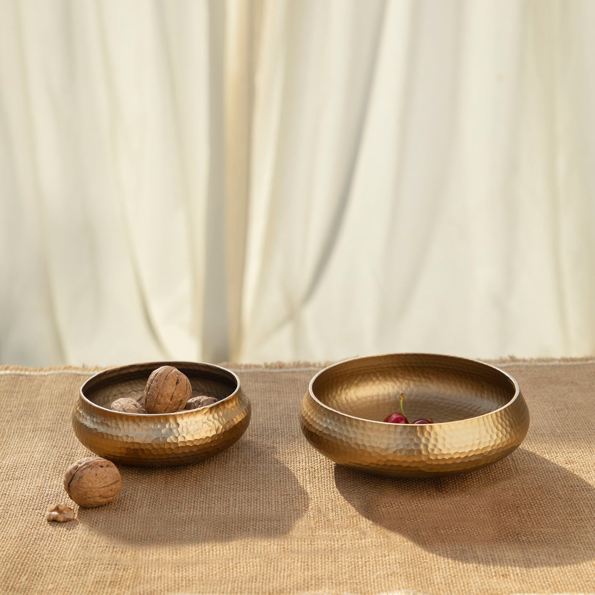 Two gold-colored bowls on a textured surface with a neutral background