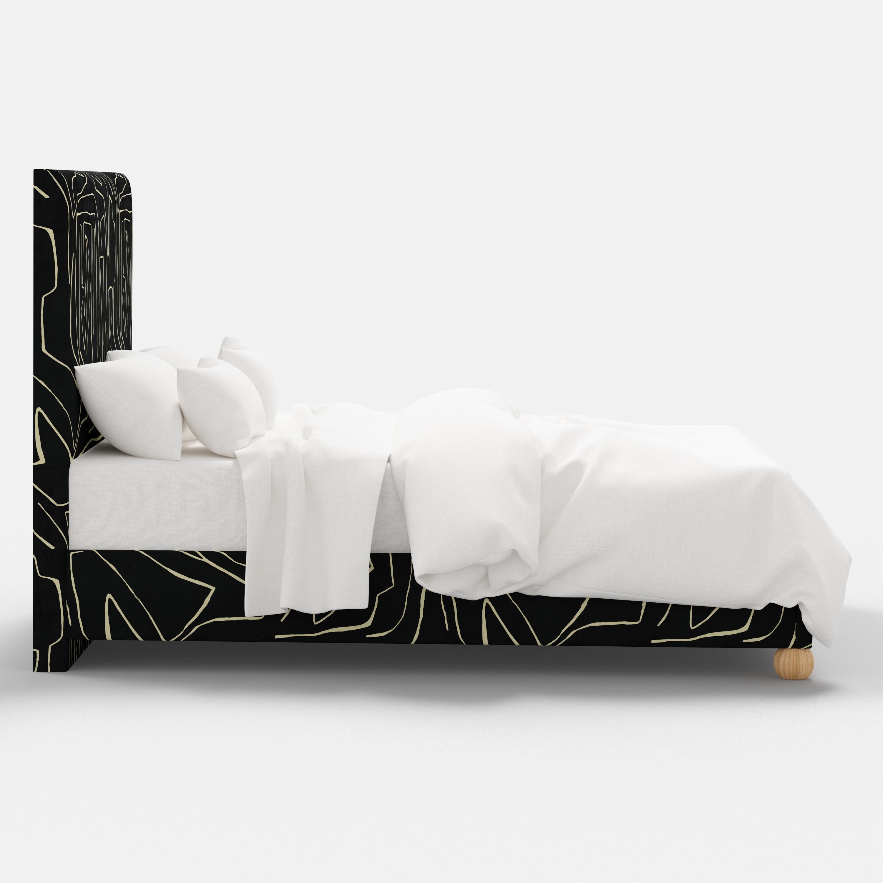 Bed with black and white abstract headboard and bedding on a white background