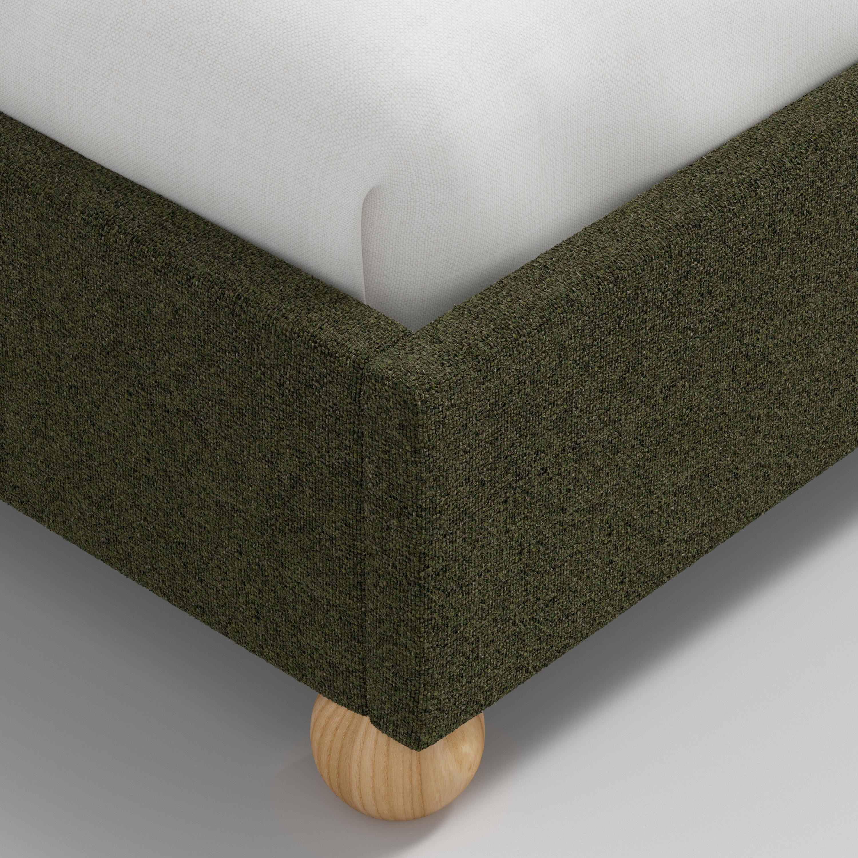 Bed with green upholstered headboard and white bedding on a white background