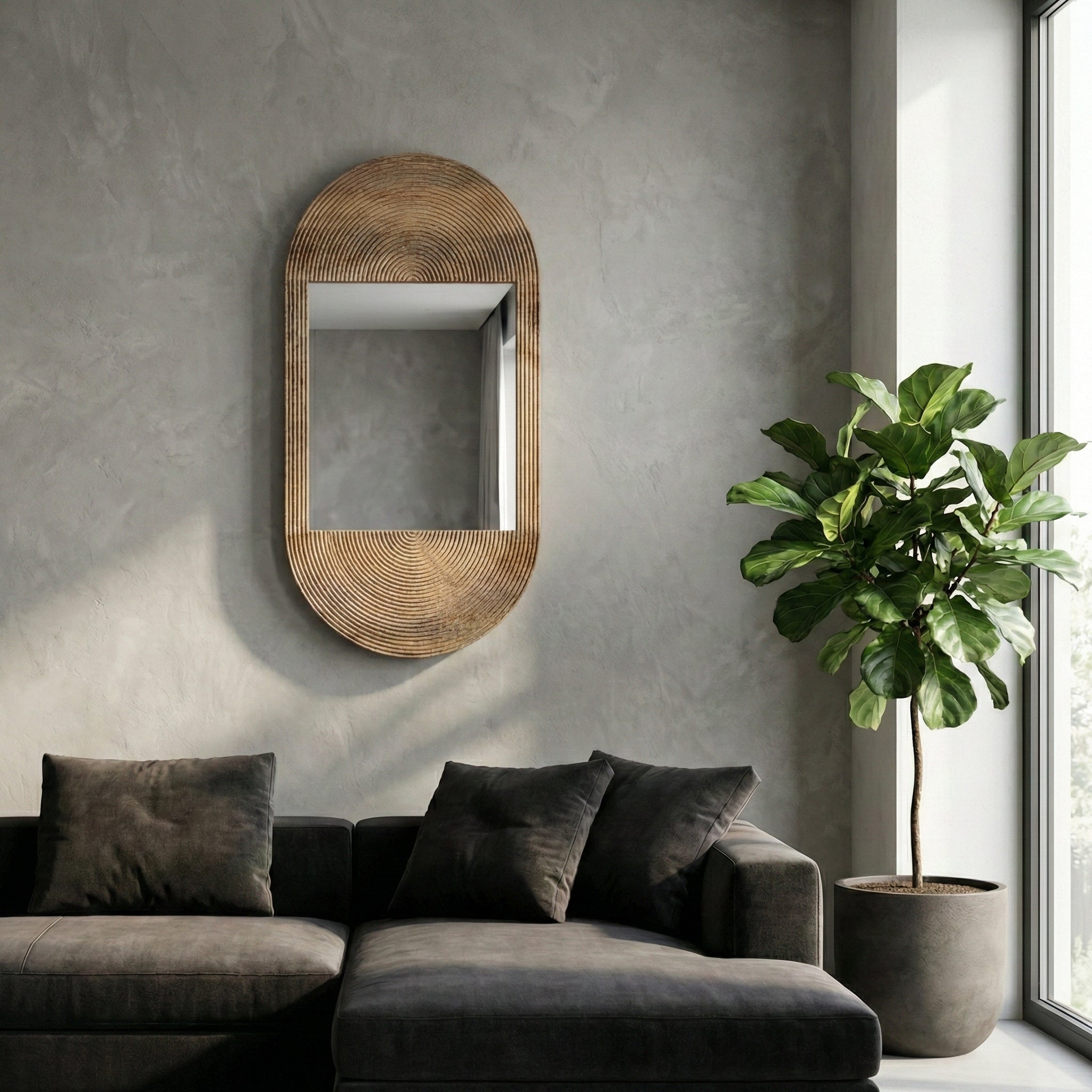 Modern living room with a textured wall, oval mirror, gray sofa, and potted plant.