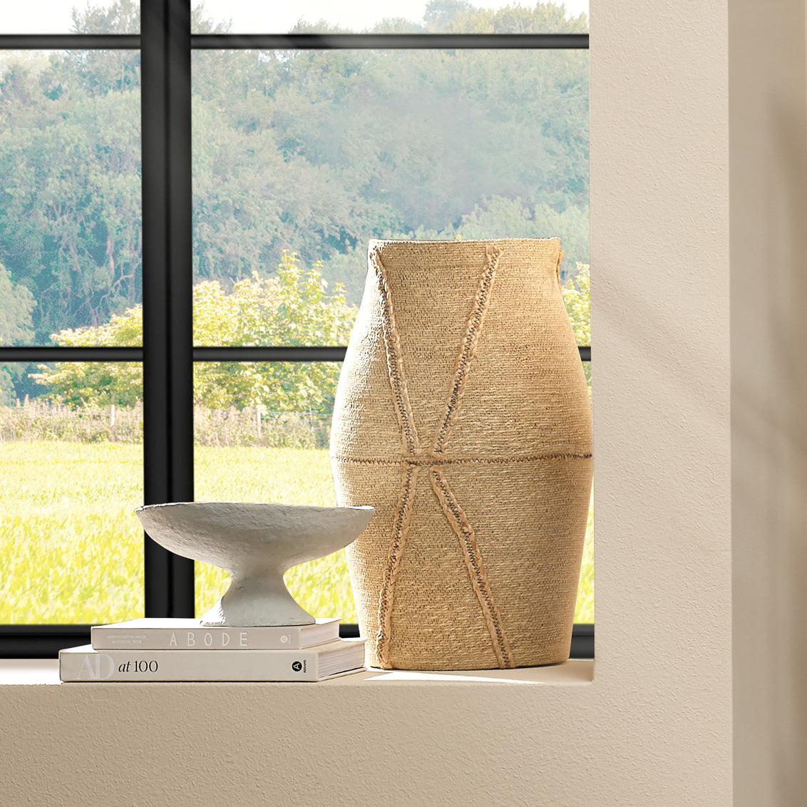 Decorative woven basket on a windowsill with a view of greenery outside
