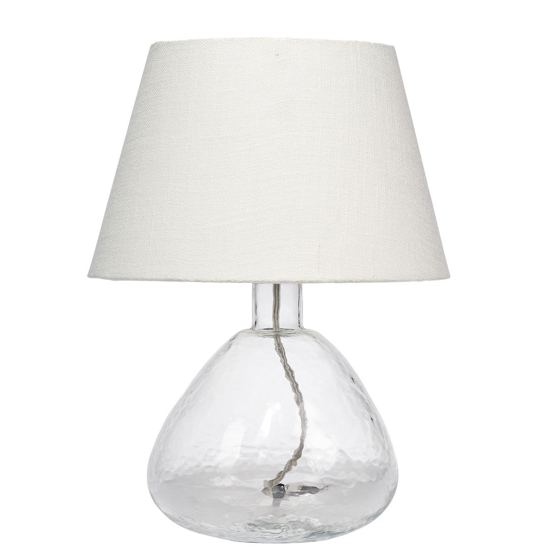 Table lamp with clear glass base and white fabric shade on a white background