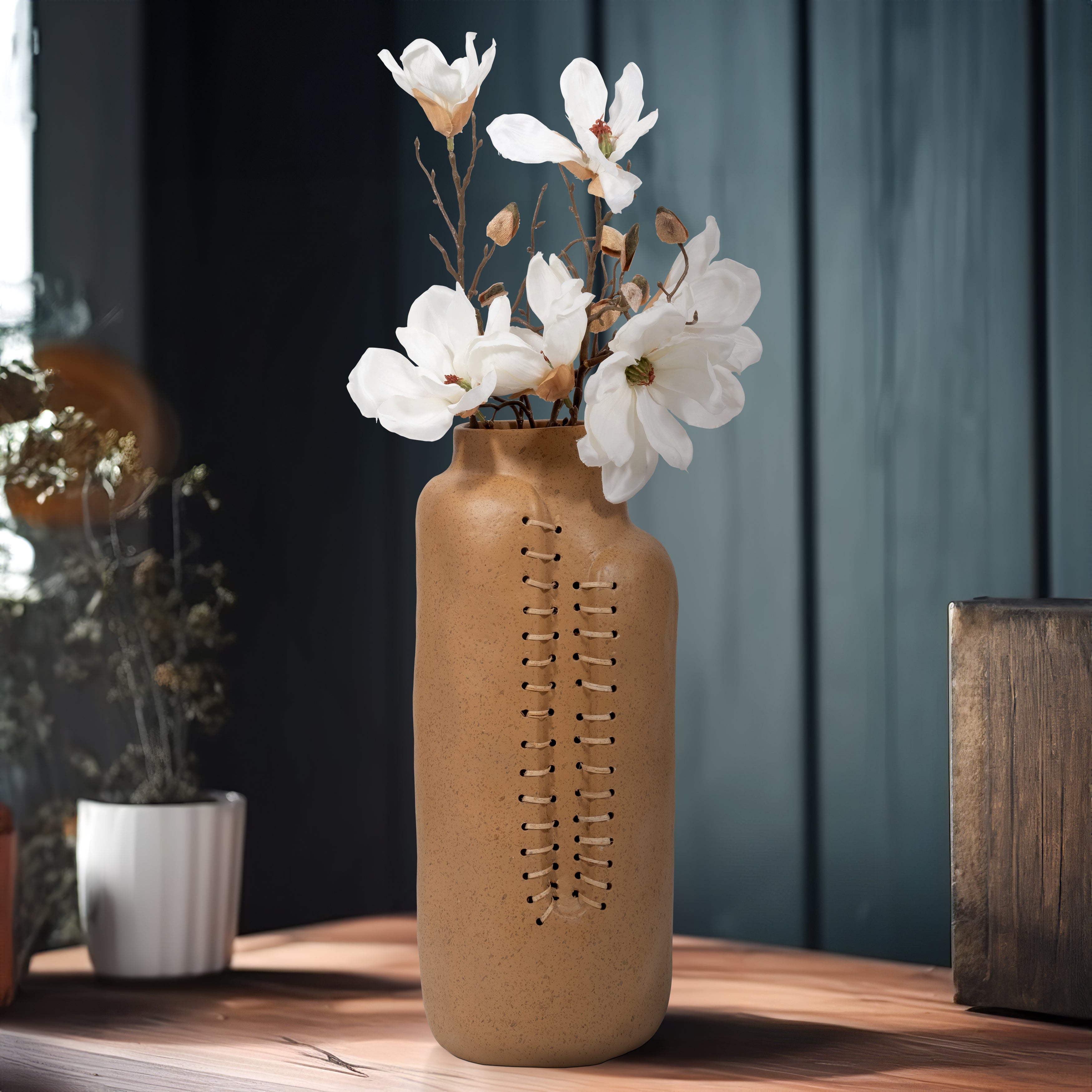 Brown vase with white flowers on a wooden surface