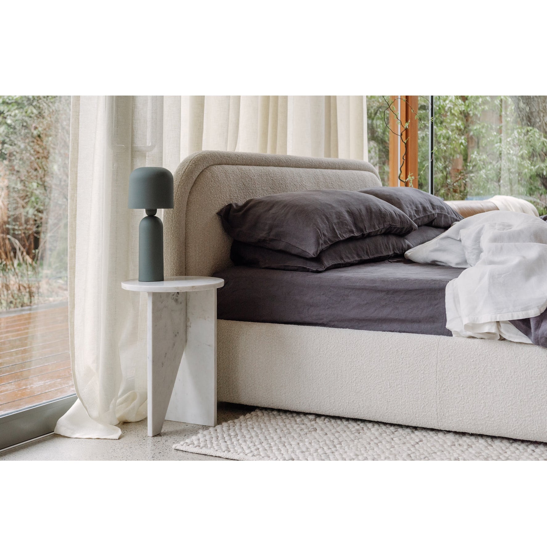 Modern bedroom with a bed, side table, and decorative lamp.