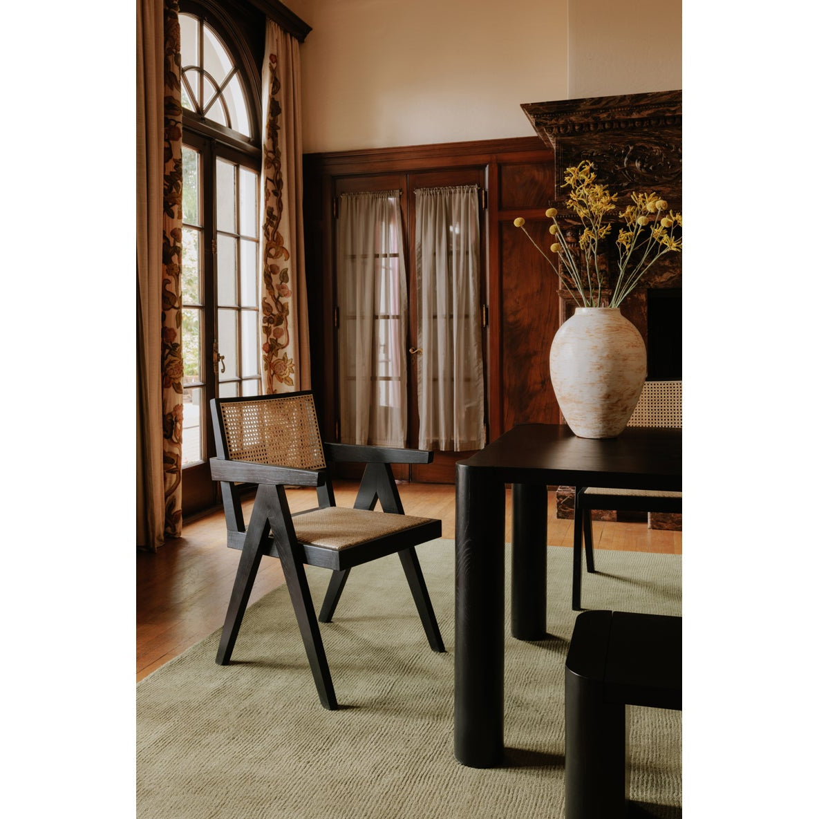 Dining room with a table and chairs, large windows, and decorative elements.