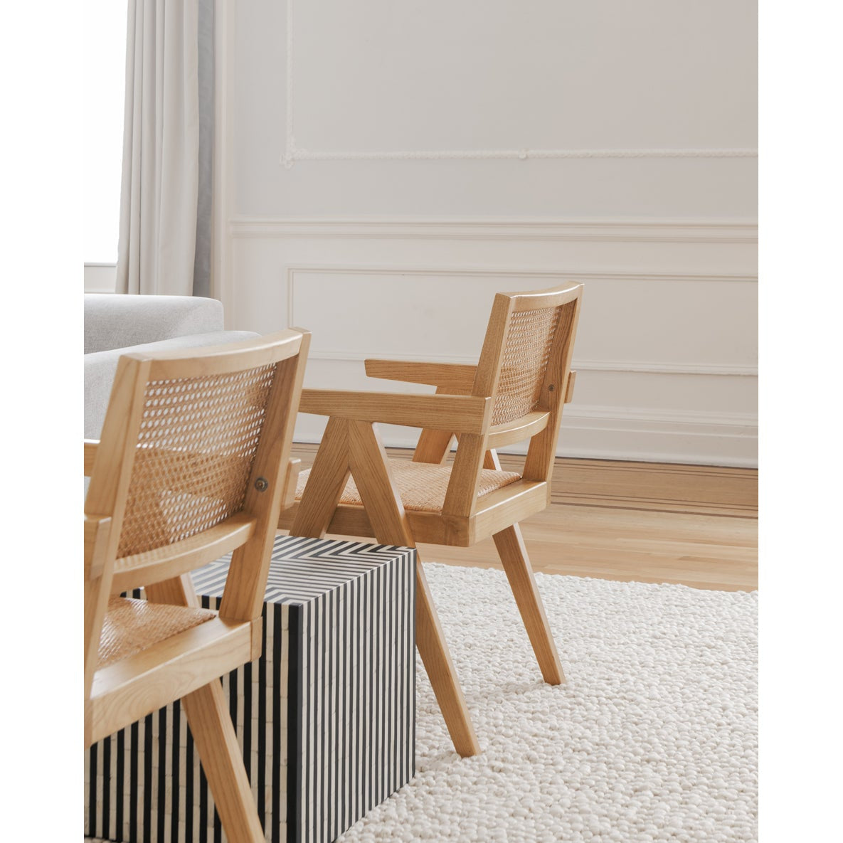 Dining area with wooden chairs and a table in a room with light-colored walls.