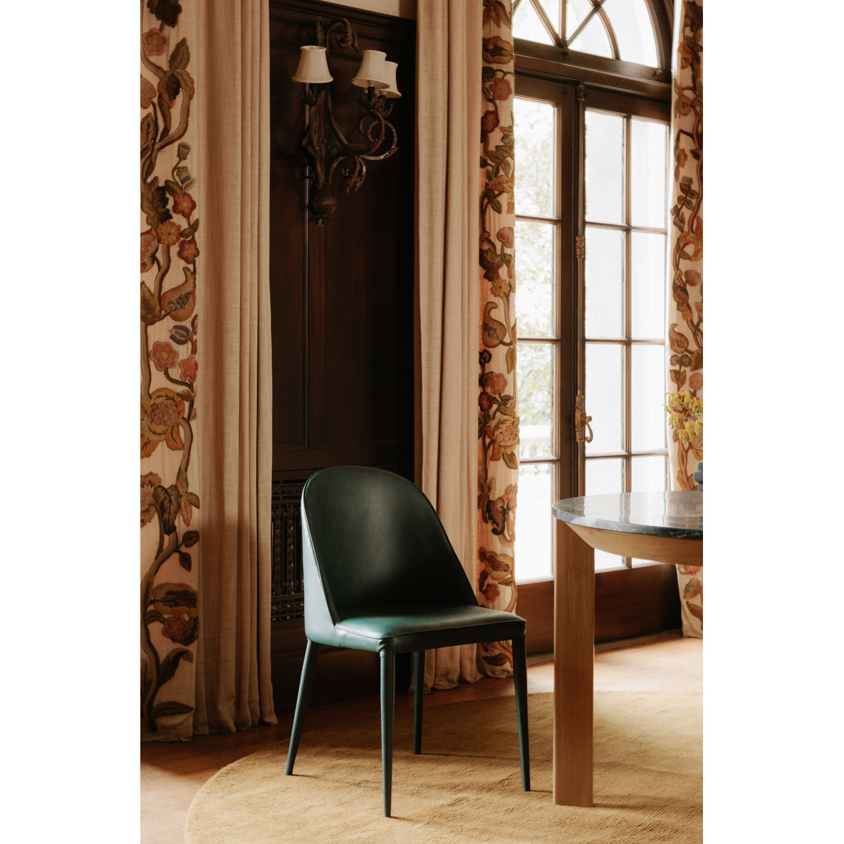 Green chair in a room with floral curtains and a window.