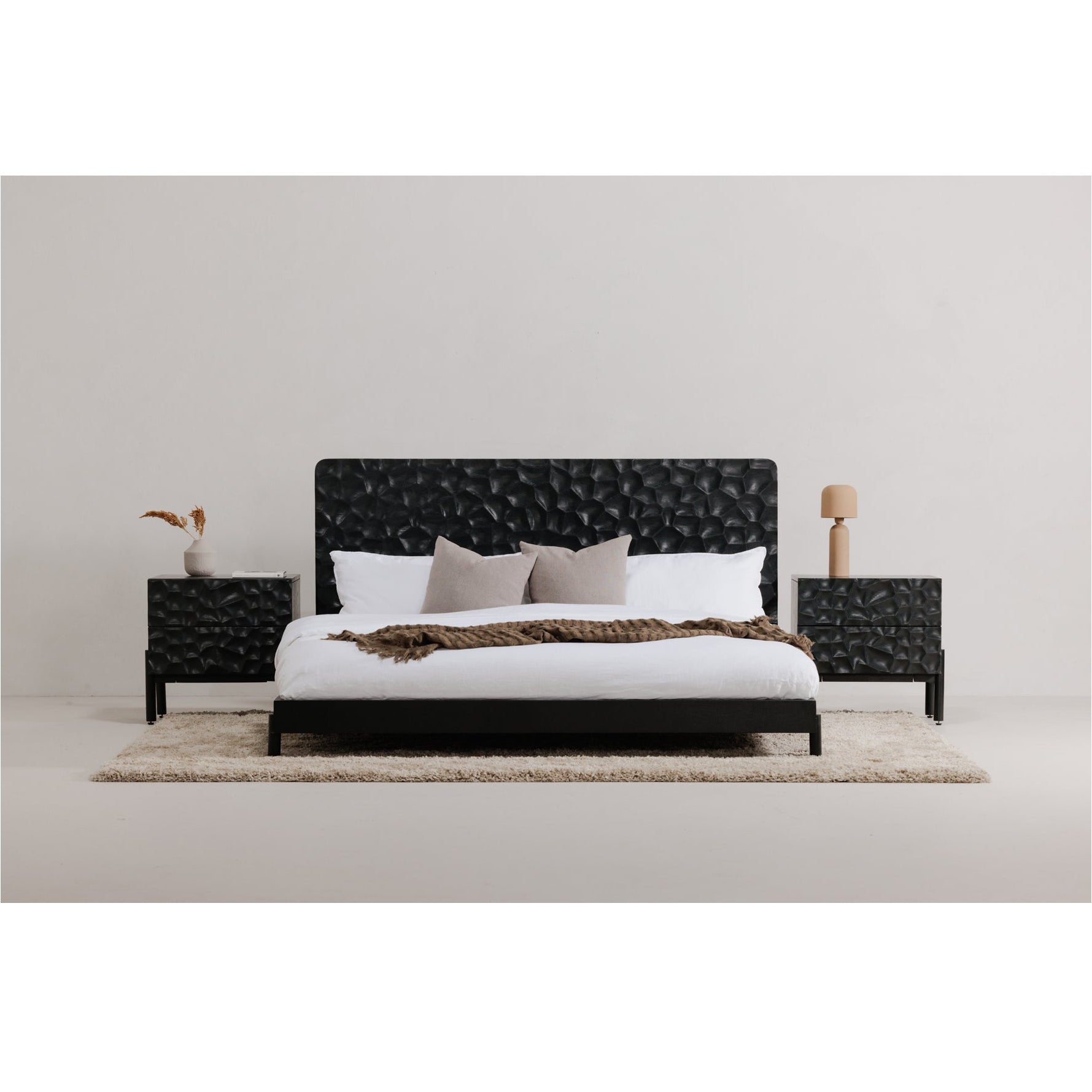 Black bed with white bedding in a minimalistic room.