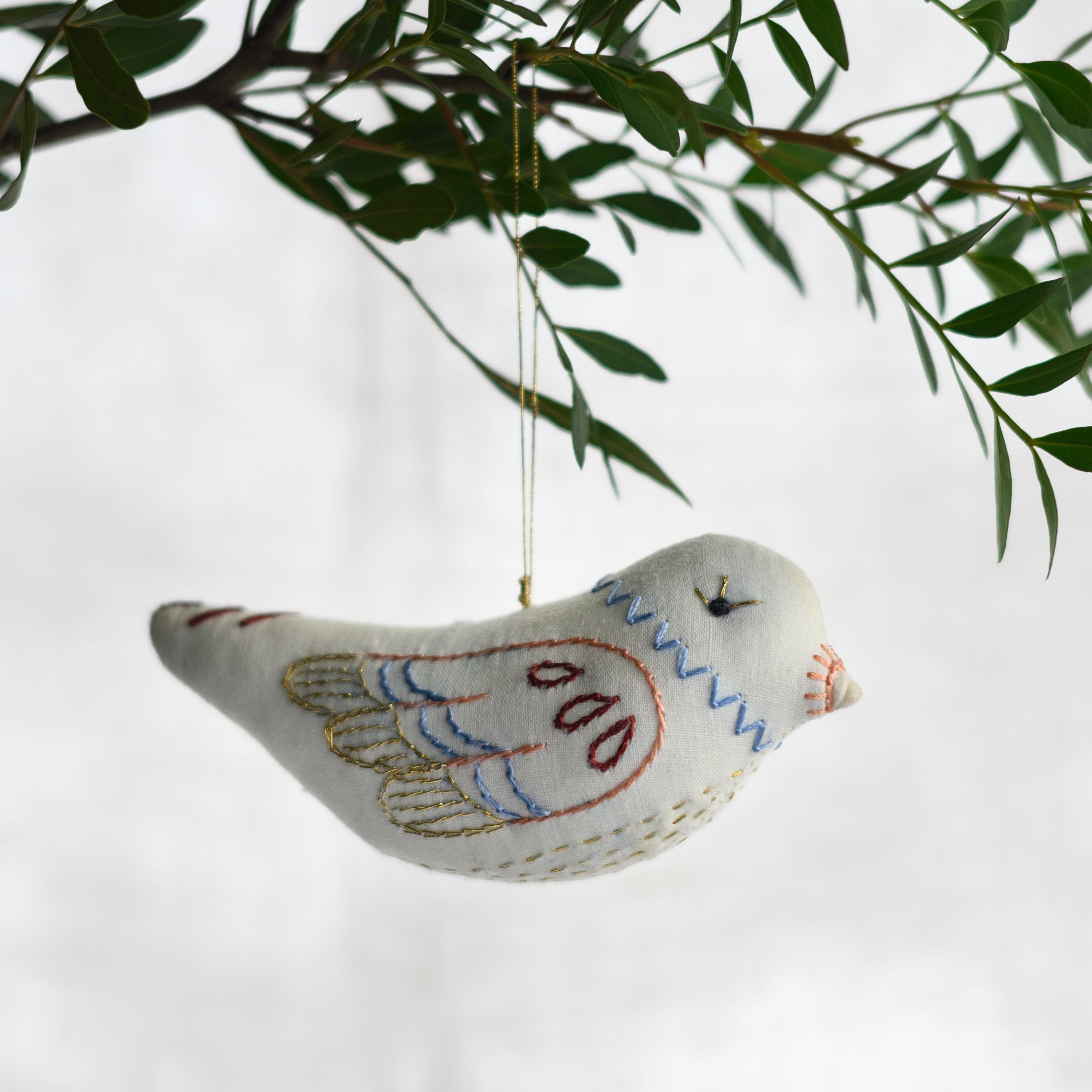 Decorative bird ornament hanging from a branch with a white background