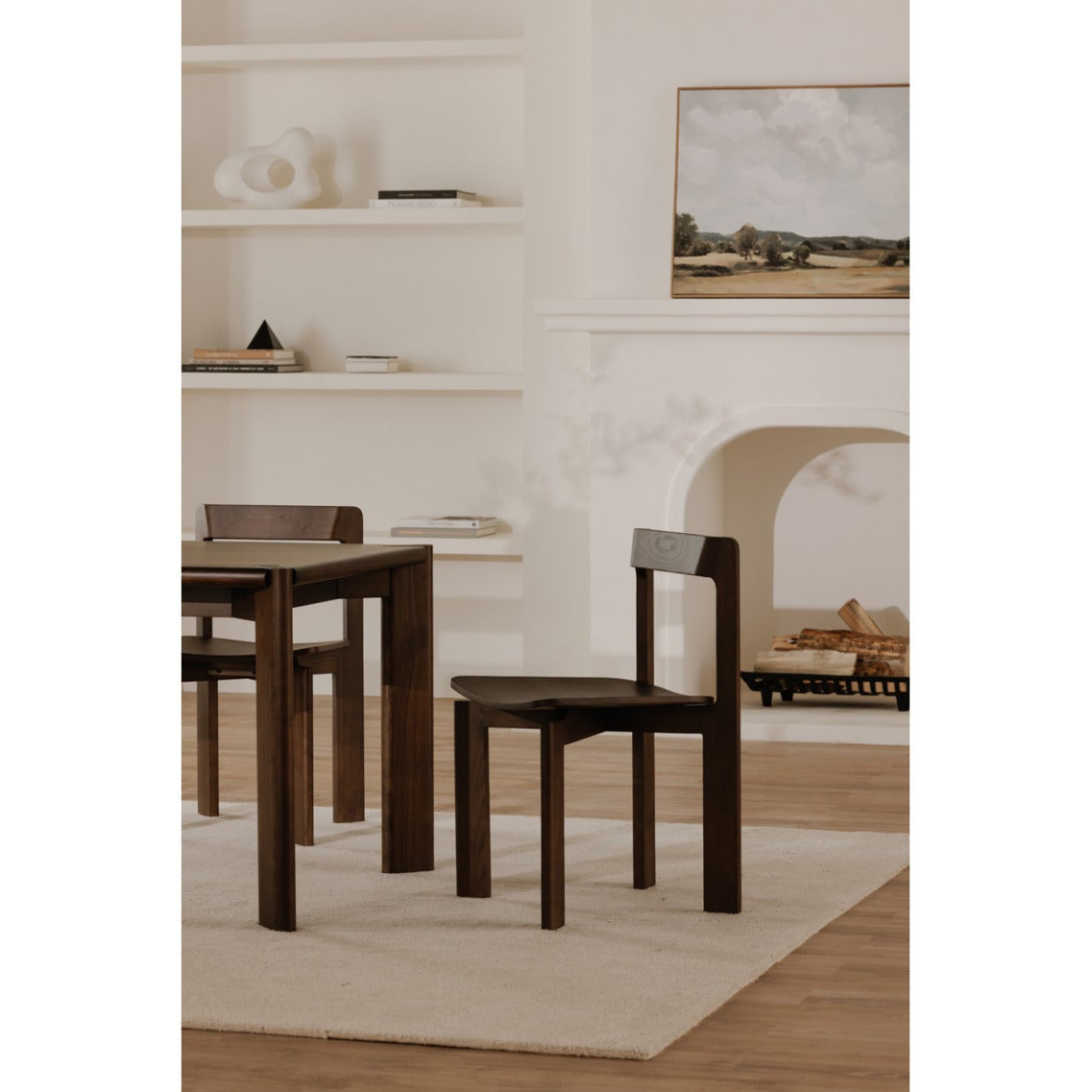 Dining room with wooden table and chairs on a light-colored rug.