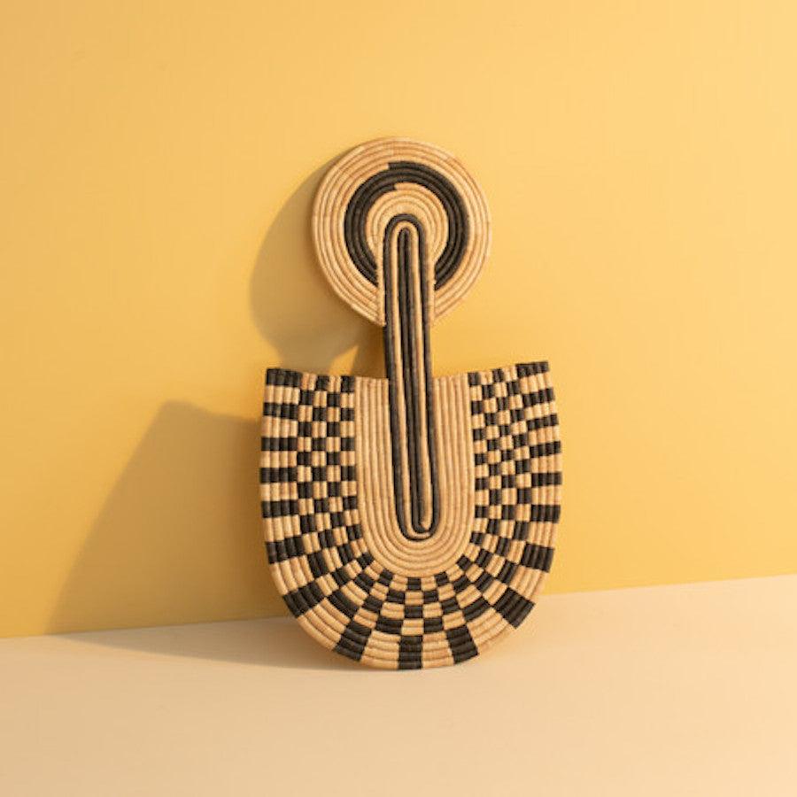 Wovenwall art with black and beige pattern on a yellow background