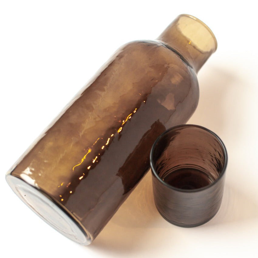 Brown glass carafe and matching glass on a white background