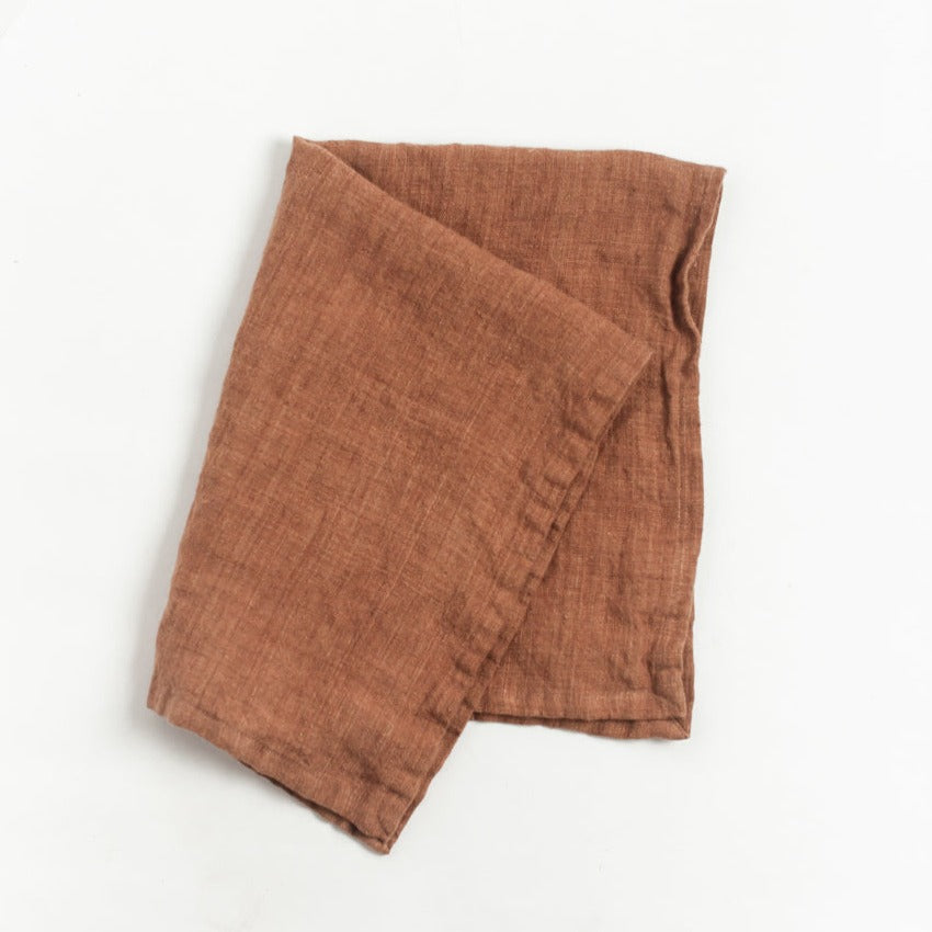 Brown linen towel folded on a white background
