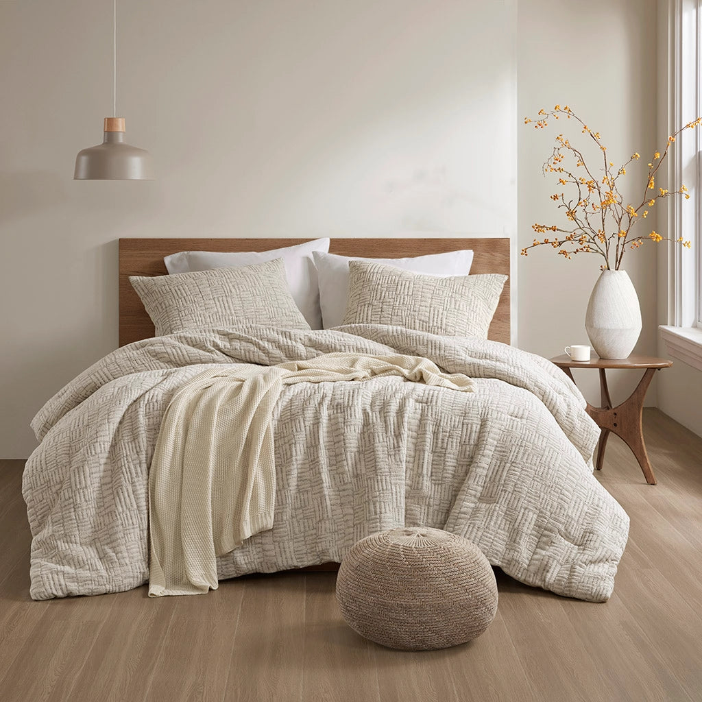 Neatly made bed with textured bedding in a bedroom setting.