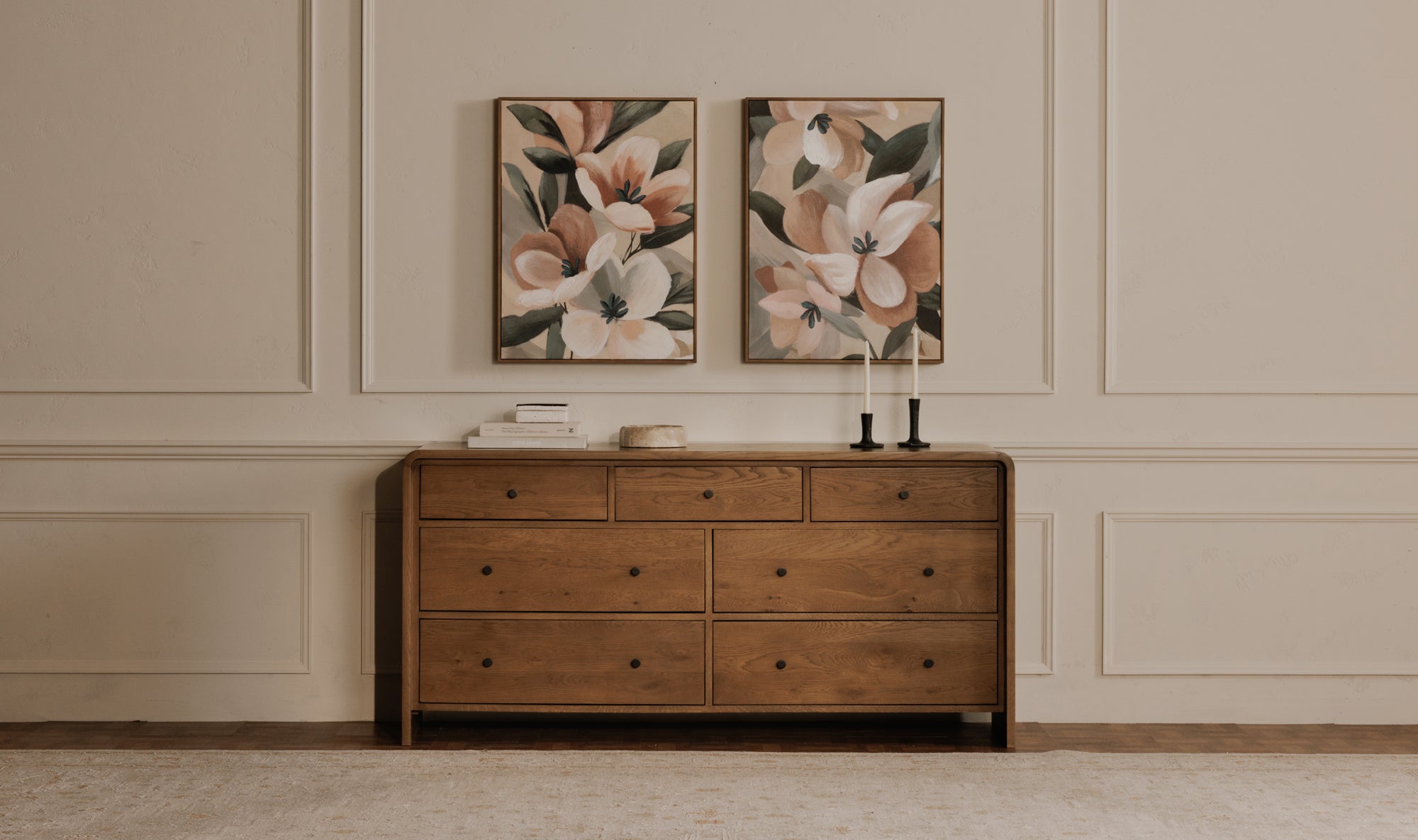 Framed artwork of floral design over a cabinet with books and candles