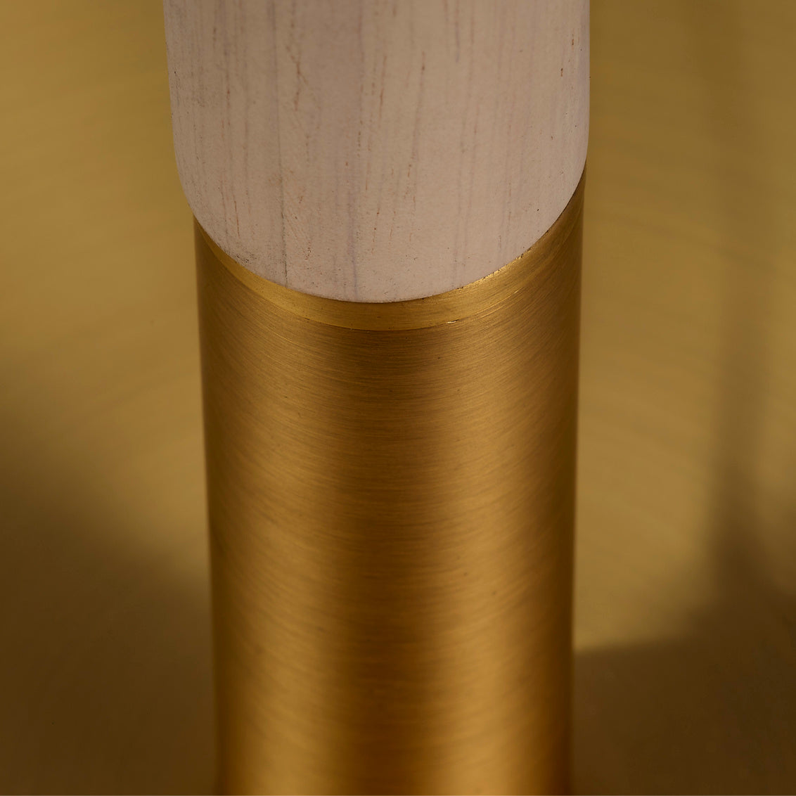 Close-up of a cylindrical object with a wooden top and brass base on a gold background