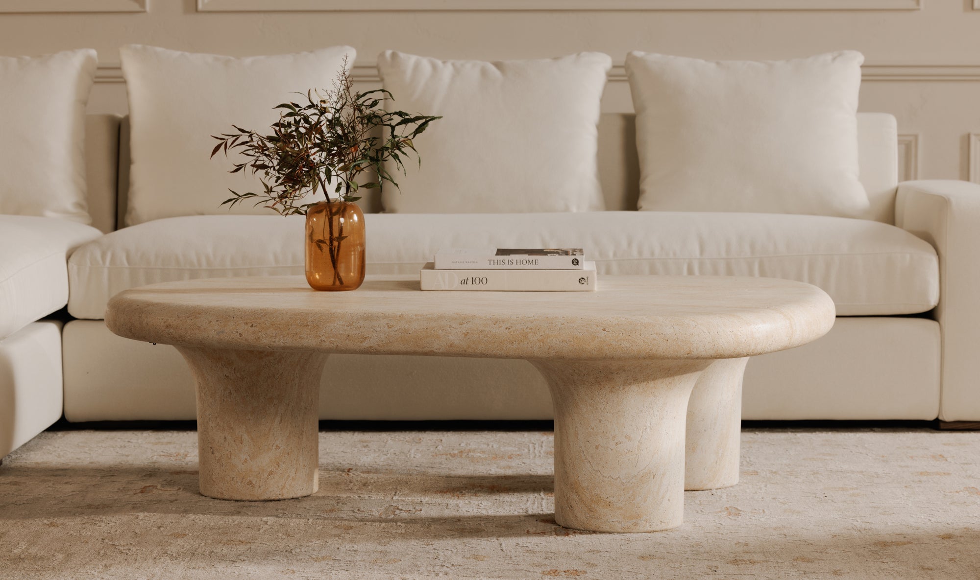 Beige sofa with a stone coffee table and decorative items in a living room setting.