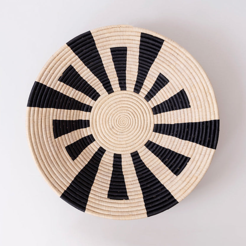 Woven basket with black and beige pattern on a light gray background