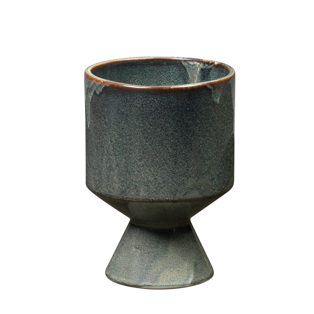 Green ceramic cup with a footed base on a white background